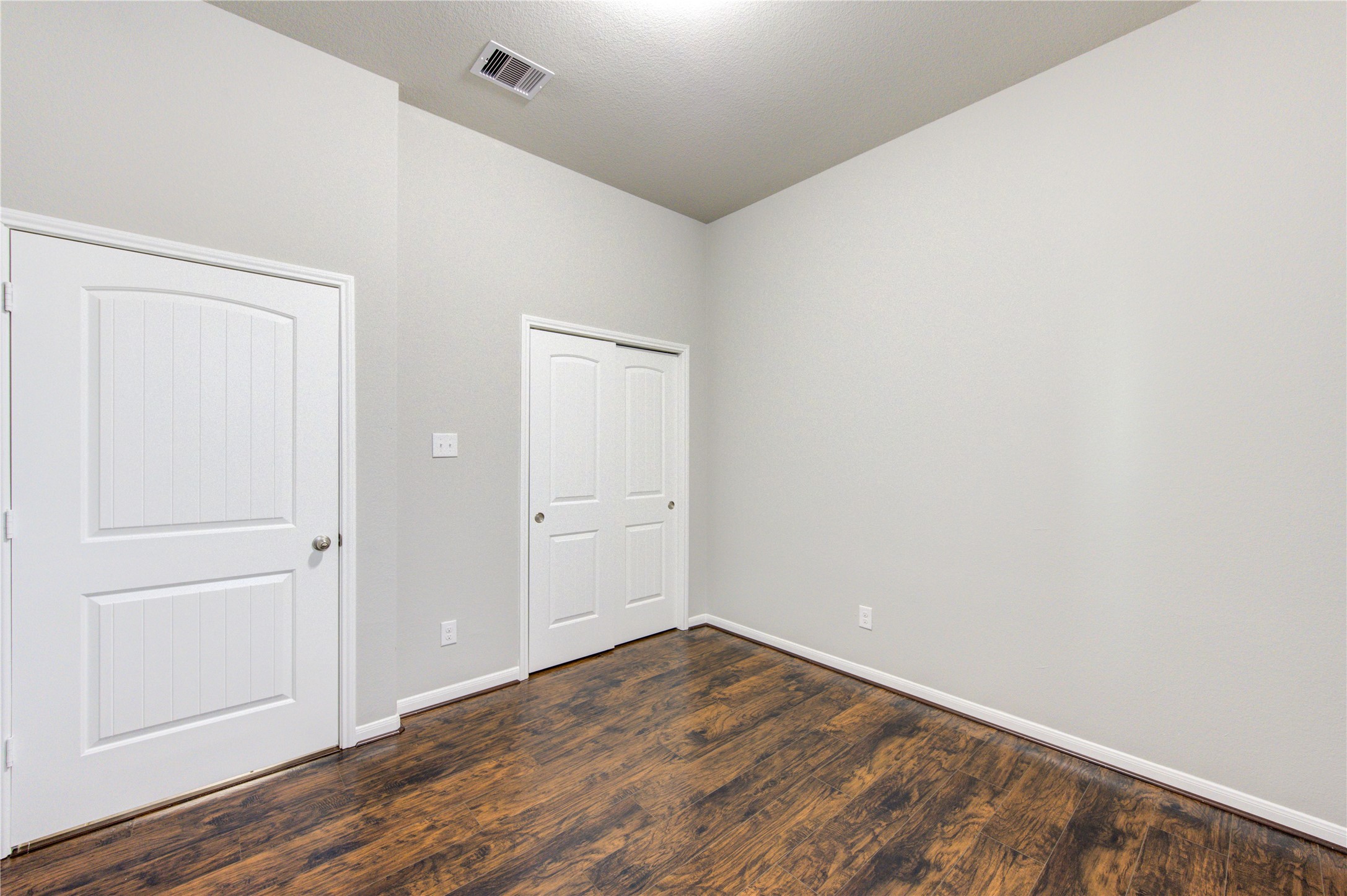 Charming single-story brick home with a two-car garage. Features a well-maintained front yard with mature trees and shrubs. The entrance is inviting with a covered porch and arched doorway, offering great curb appeal.