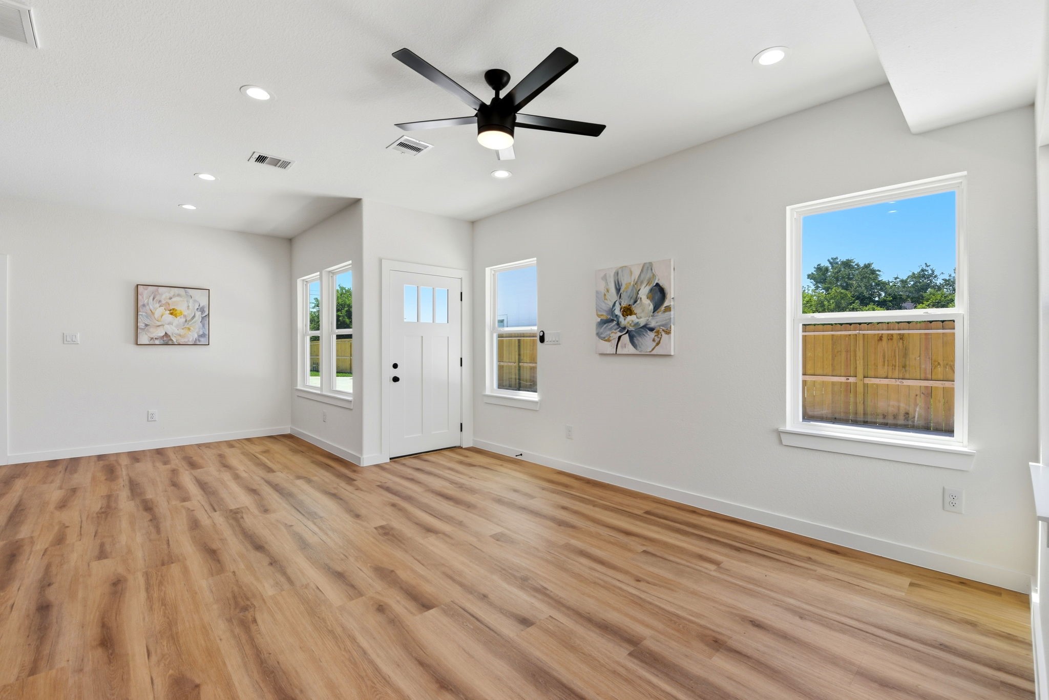 A bright, open living space and dining area with large windows, water resistant vinyl plank flooring, and modern lighting.