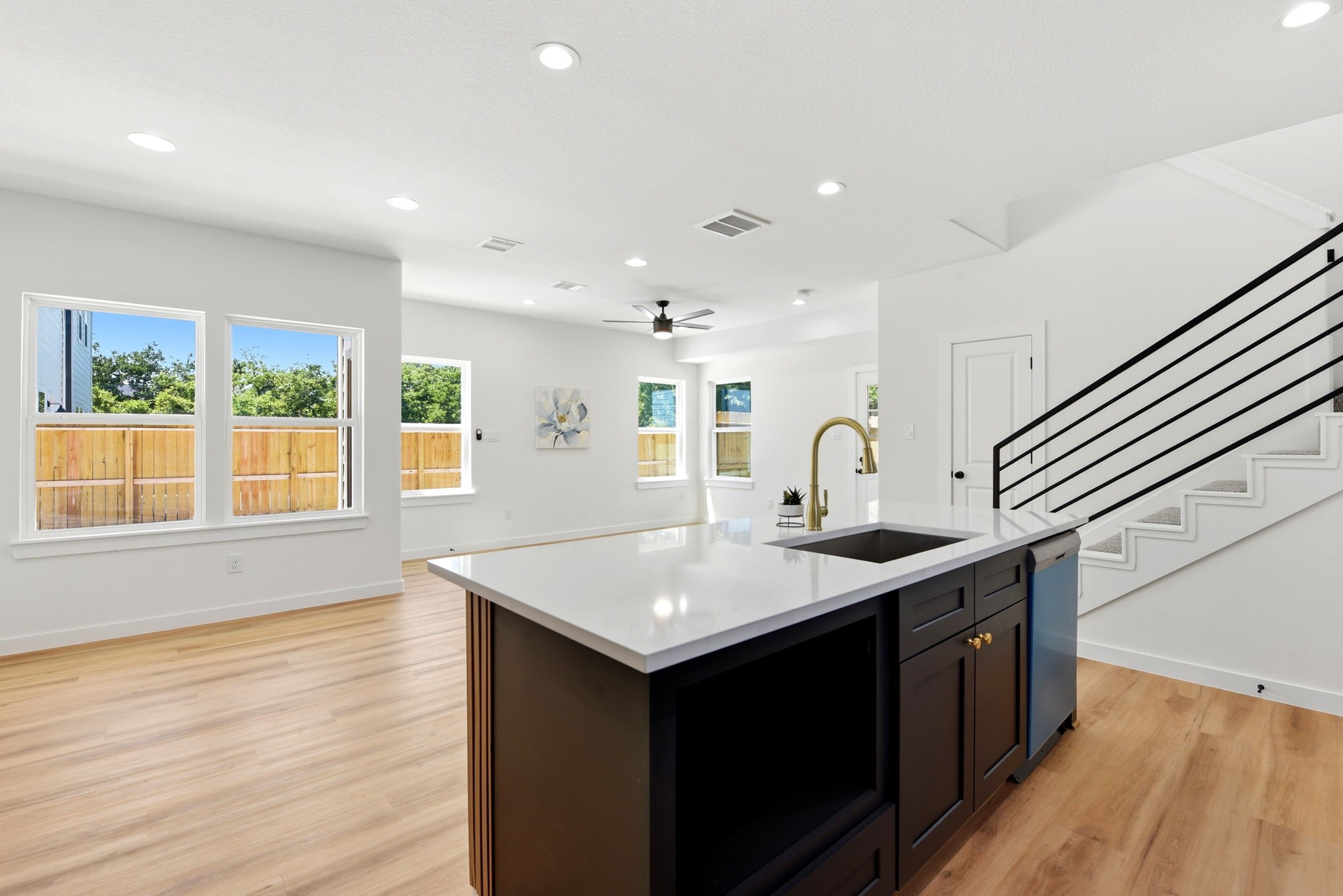 Bright, open-concept living space with large windows, modern kitchen island with microwave.