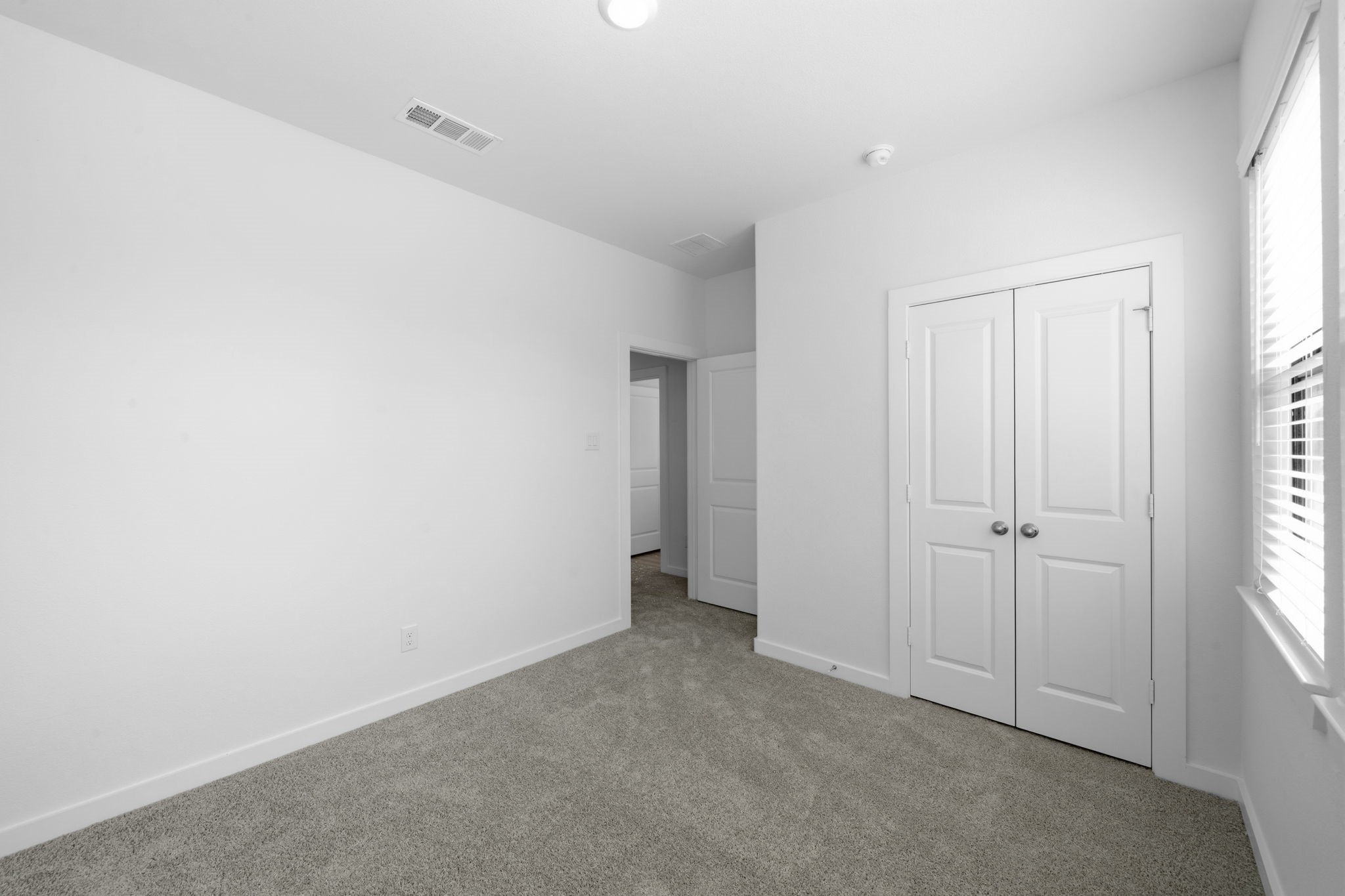 The second upstairs bedroom offers a comfortable retreat with plush carpeting, a spacious double-door closet, and a bright, neutral backdrop. With plenty of room to personalize, this inviting space is ready to become your own.