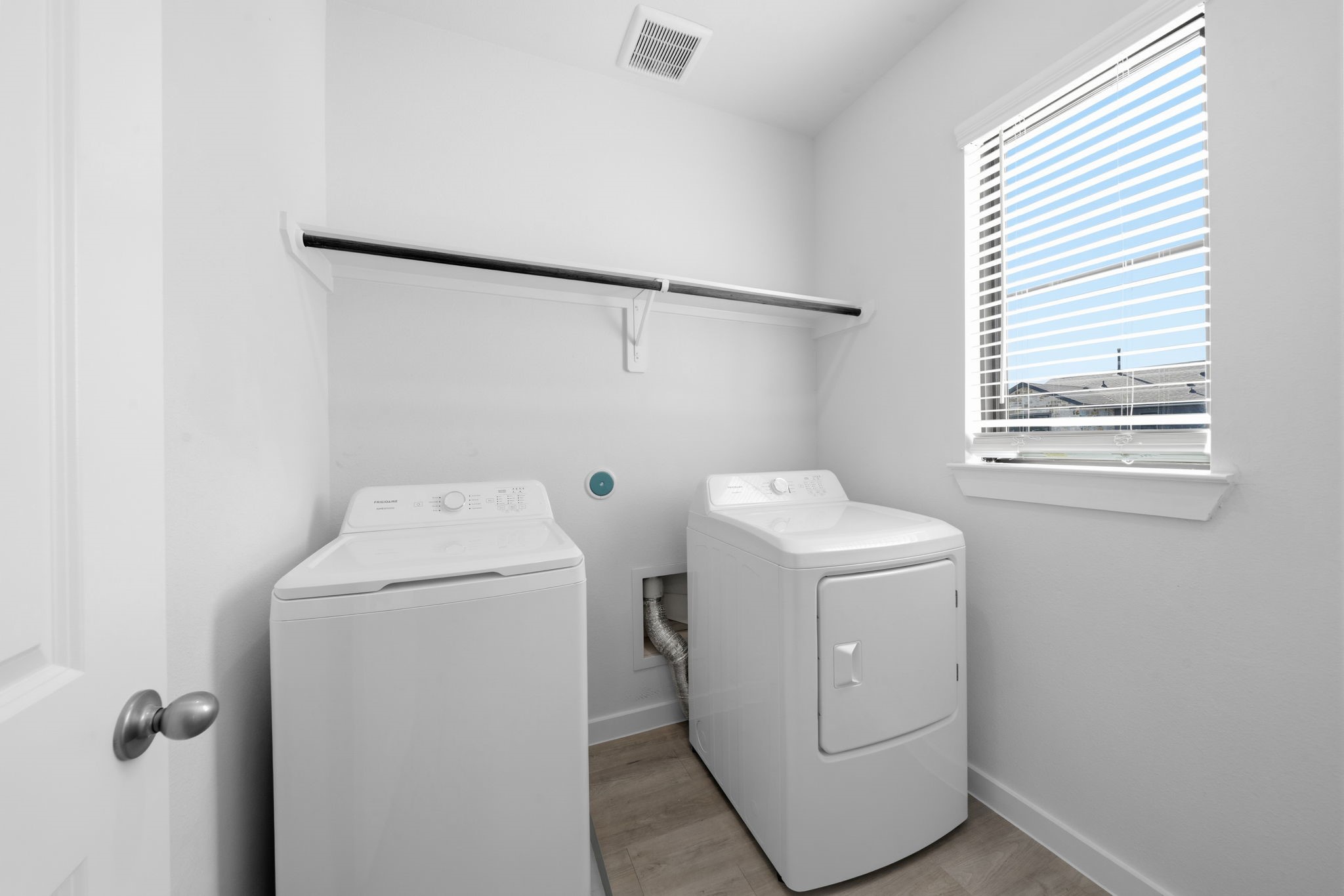Conveniently located upstairs, the dedicated laundry room makes everyday routines feel a little easier. With a full-size washer and dryer, built-in hanging space, and a window bringing in natural light, this practical space keeps laundry close to where you need it most.