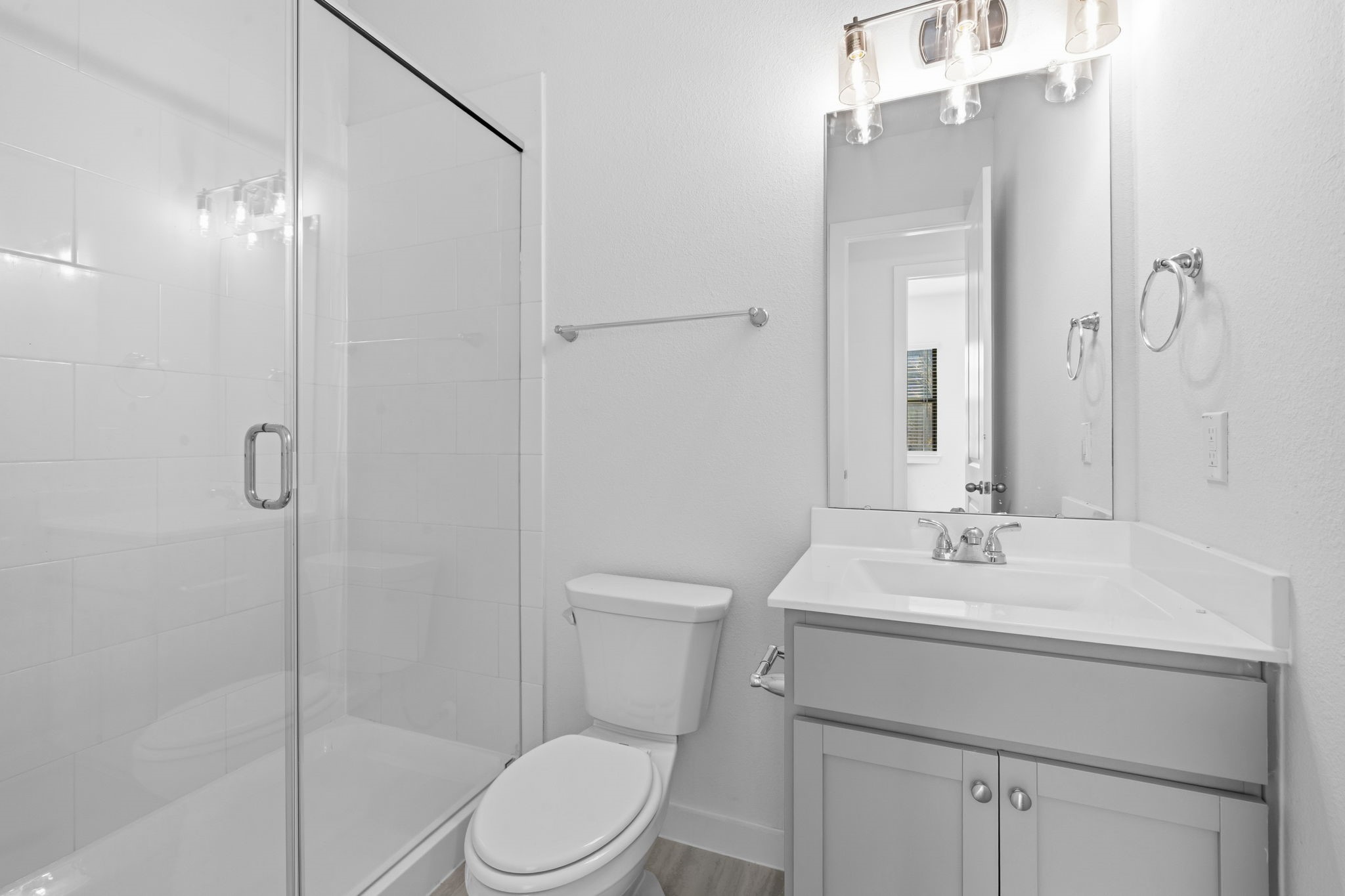 Just steps away from the main living room, this downstairs full bath offers everyday convenience for both family and guests. A sleek glass enclosed walk in shower, modern vanity, and contemporary lighting create a clean, polished space that feels both functional and inviting.