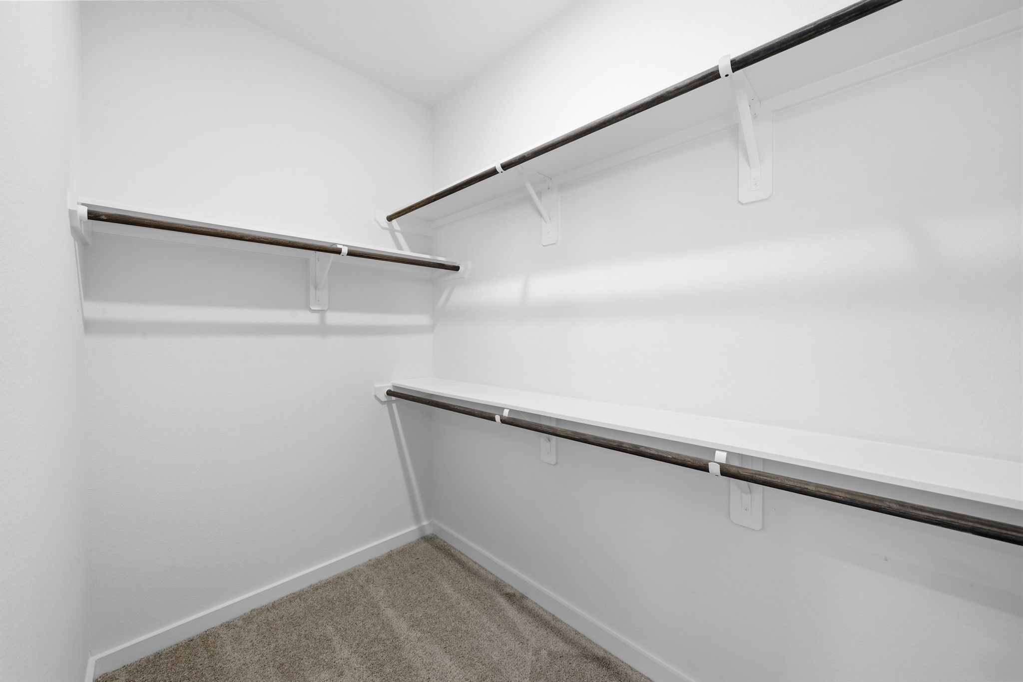 The primary suite continues with a spacious walk-in closet, offering plenty of room to organize your wardrobe with ample hanging space and built-in shelving.