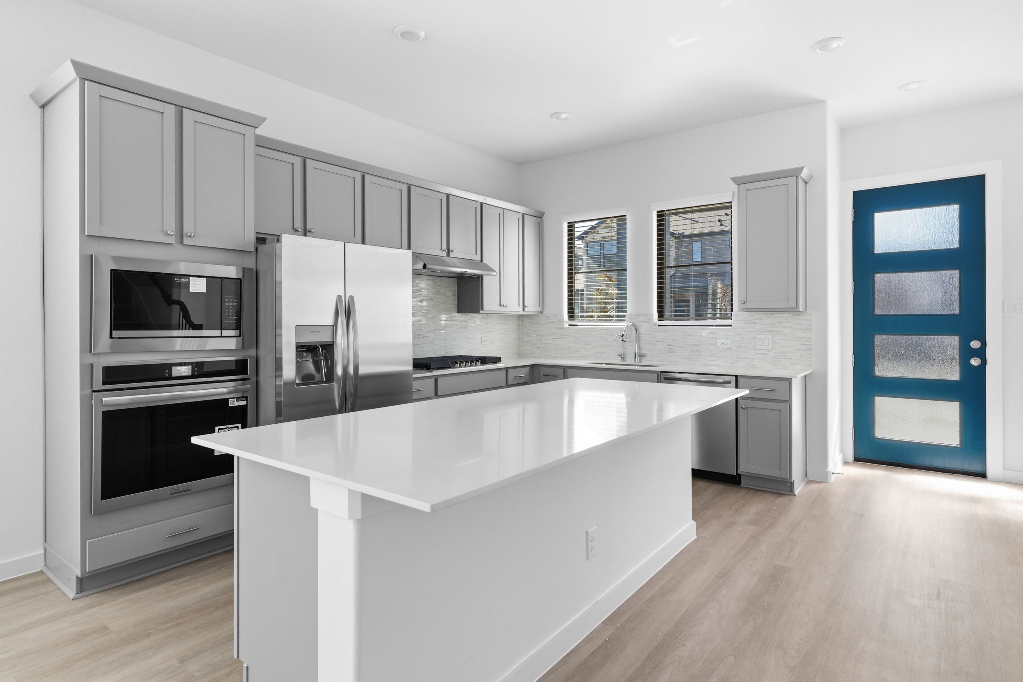 Step into your new home and feel instantly welcomed by a bright, sophisticated kitchen designed for both everyday living and memorable gatherings. With elegant gray cabinetry, a striking backsplash, stainless steel appliances, and an oversized central island, this inviting space gives you room to cook, gather, and make it your own.