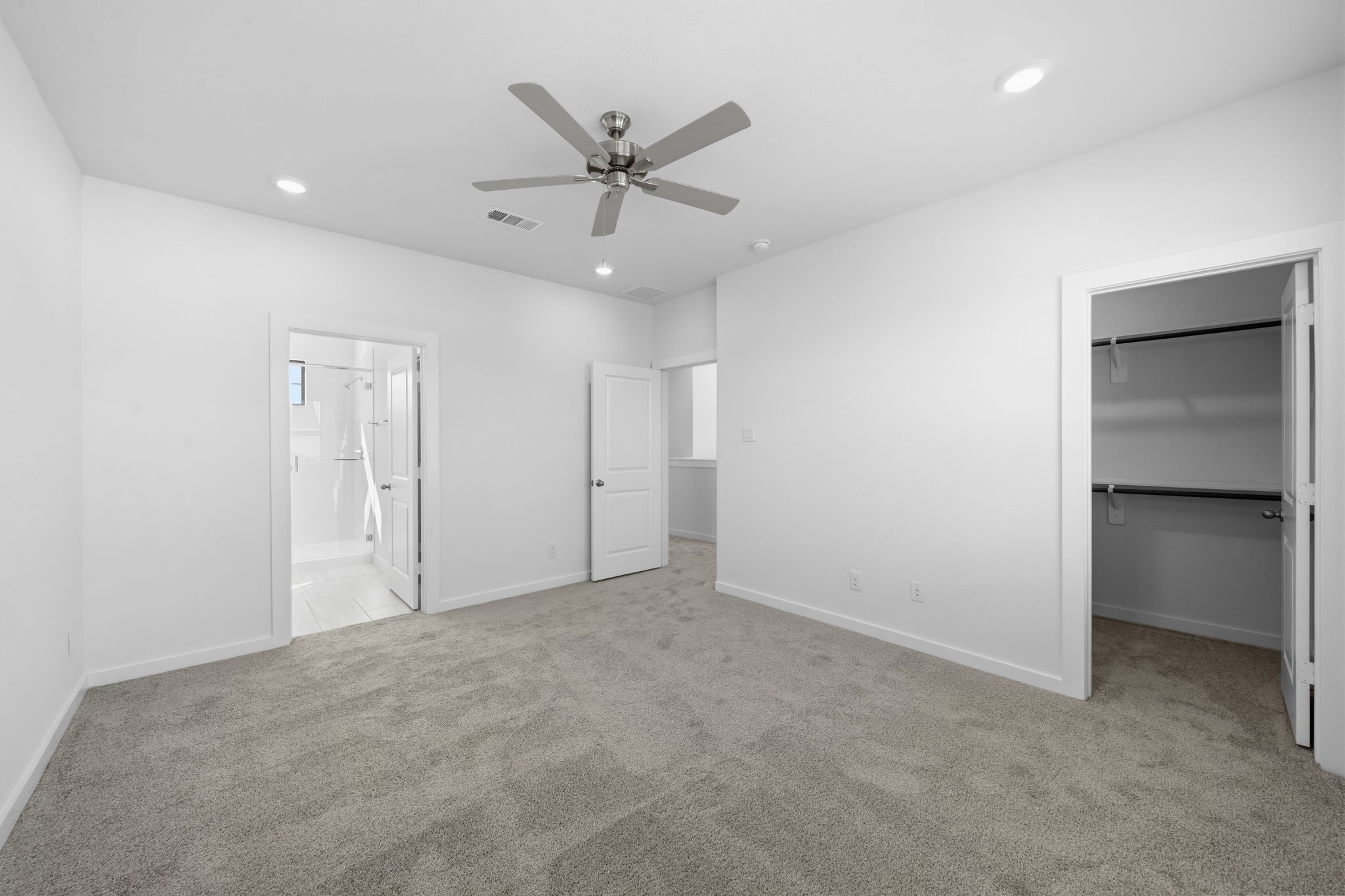 The primary suite welcomes you with generous space, plush carpeting, and a calming neutral palette that makes it easy to settle in and feel at home. With recessed lighting, a ceiling fan, a spacious walk in closet, and direct access to the en suite bath, this is a space designed for comfort and everyday retreat.
