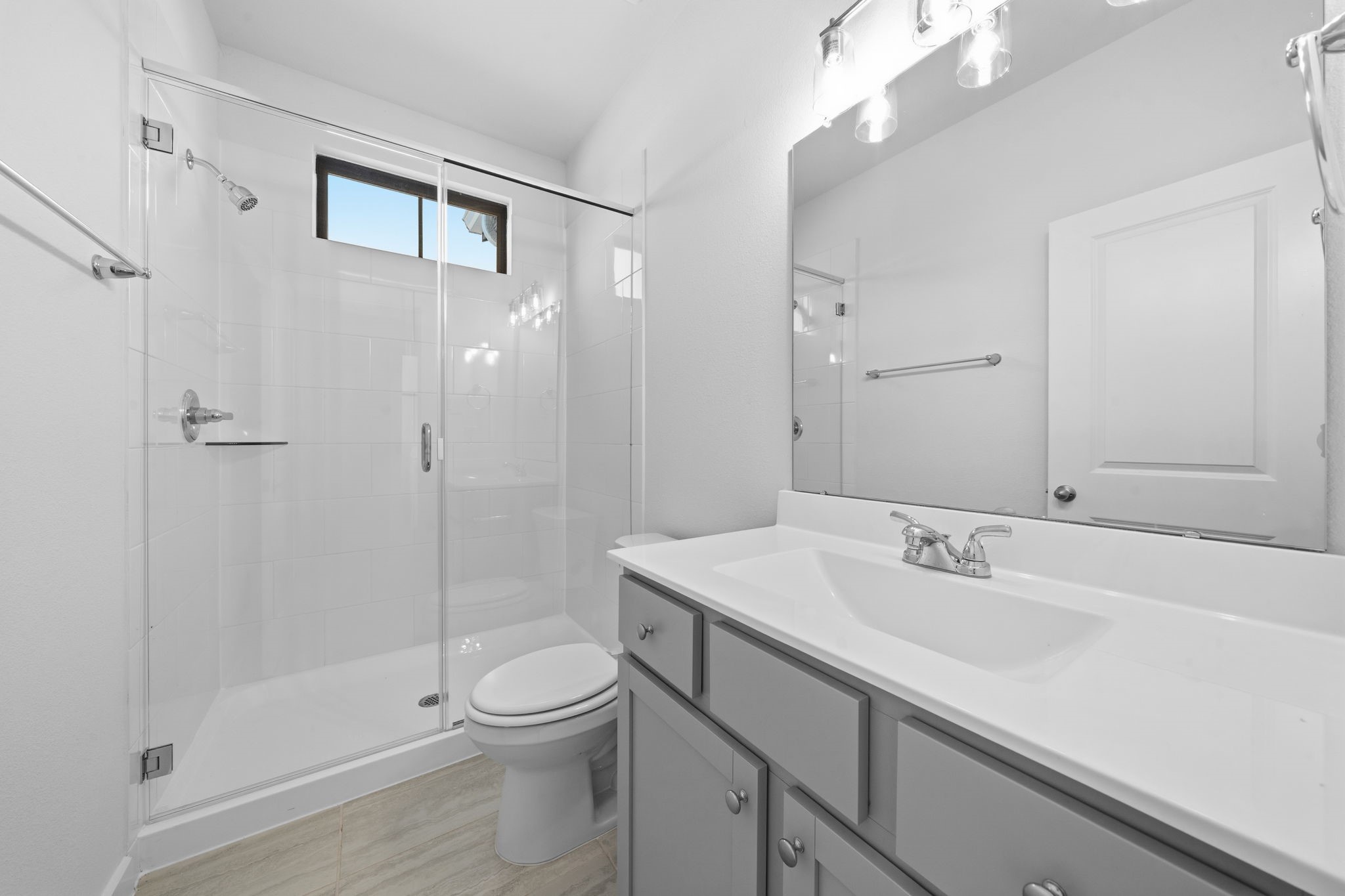 The upstairs bathroom continues the homes modern, sleek feel with a spacious walk-in glass shower, clean finishes, and a large vanity. A well-placed window brings in natural light, creating a bright and refreshing space.