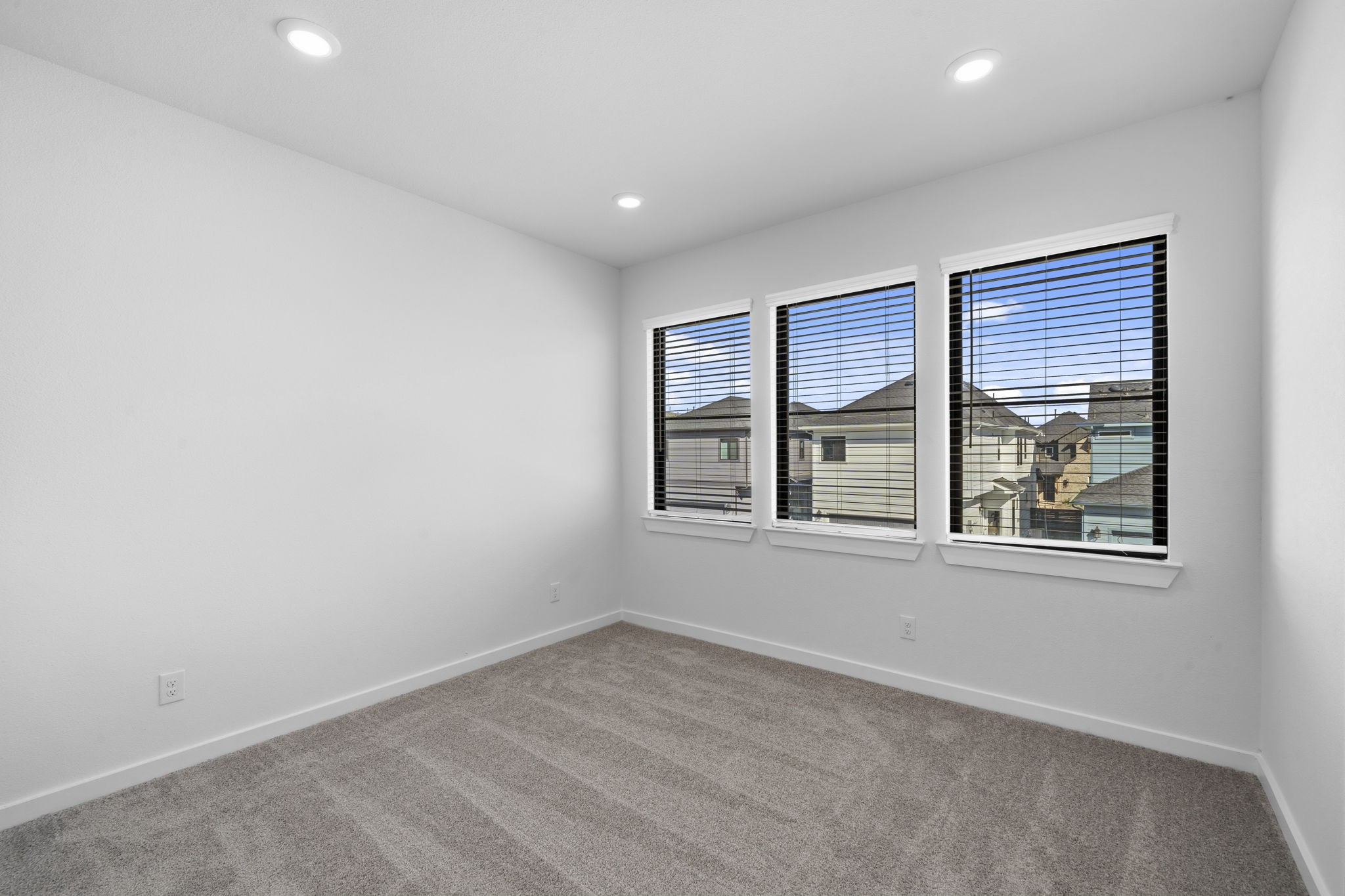 Another view of the upstairs loft showcases three large windows that fill the space with beautiful natural light and offer an open neighborhood view. With plenty of room to furnish and personalize, this versatile area can easily become a cozy second living space, game room, or quiet retreat.