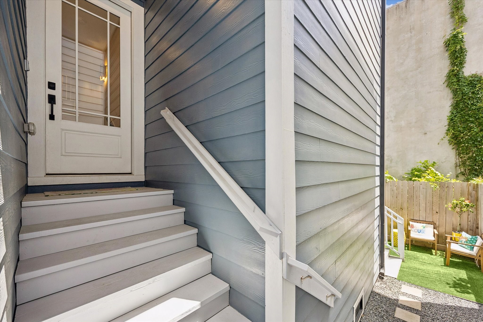 The entry feels tucked away and private with covered stairs, a charming cottage-style door, and easy access to the small fenced yard for a little extra outdoor enjoyment.