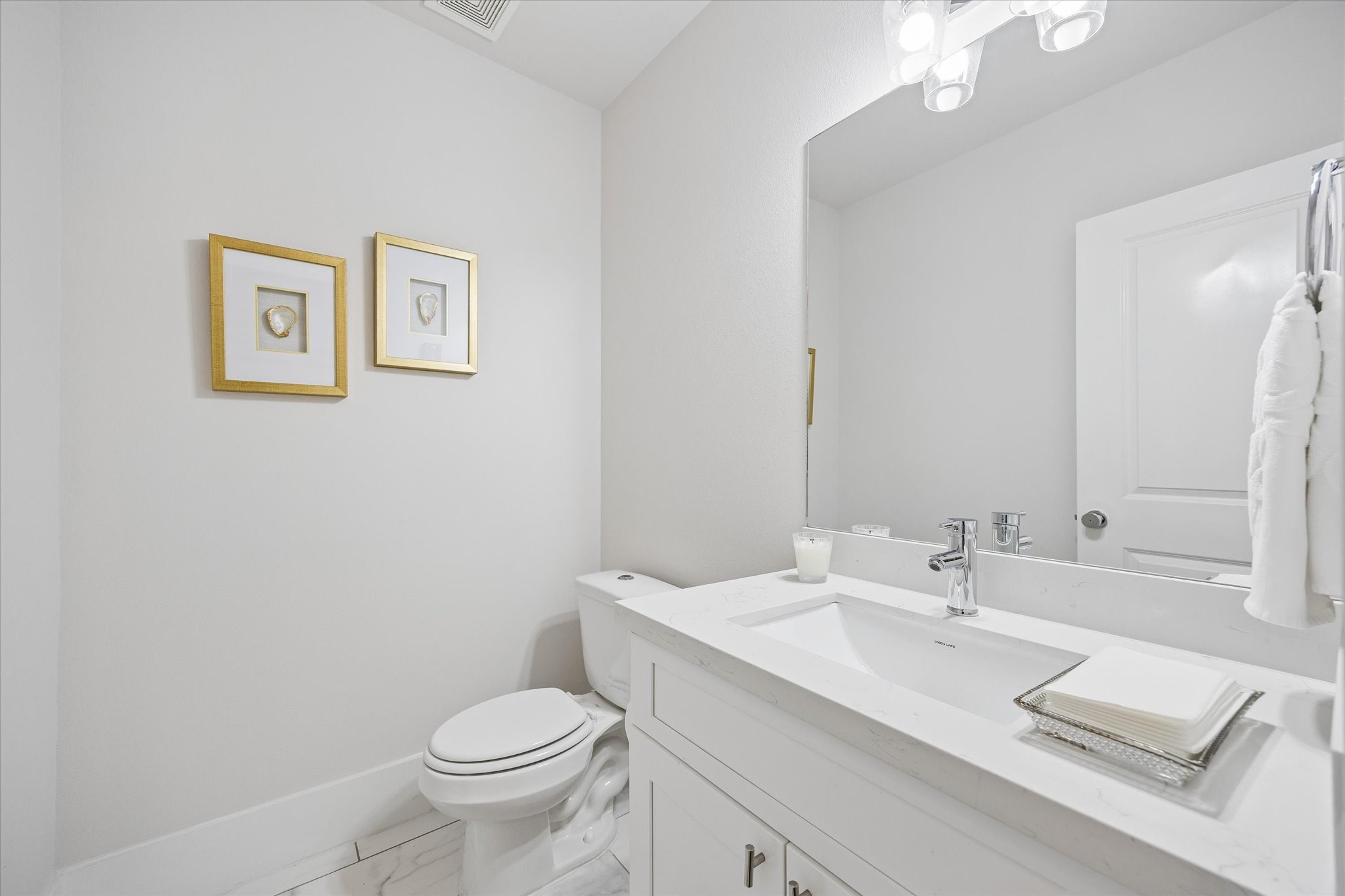 The main floor powder bath is perfect for guests and daily use with crisp, clean finishes, a sleek vanity, designer lighting, and a polished look that feels fresh and easy to maintain.