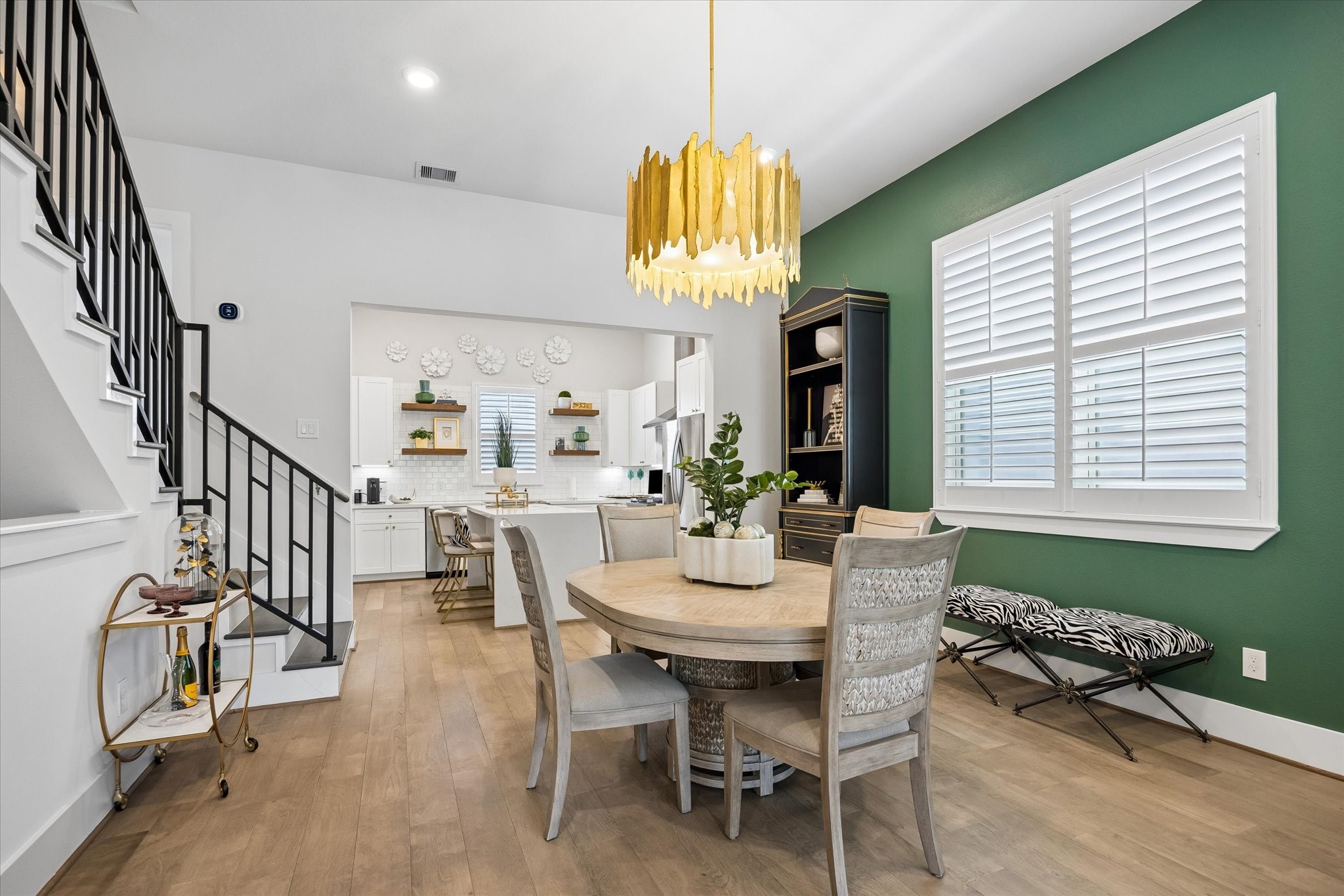 This dining area blends style and function together beautifully with engineered wood flooring, wood shuttered windows, designer lighting, and an easy connection to the island kitchen and living area.
