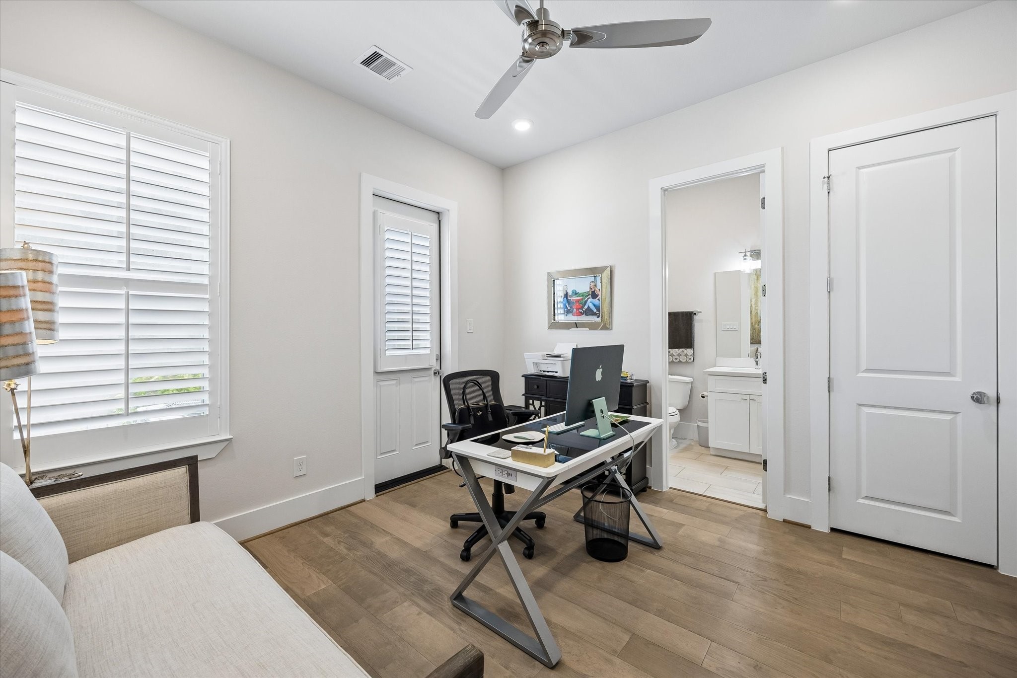 This first-floor guest suite offers a comfortable private retreat with engineered wood flooring, wood shuttered windows, a charming cottage-style door to the back deck and small fenced area, a walk-in closet, and its own ensuite bath for everyday ease.