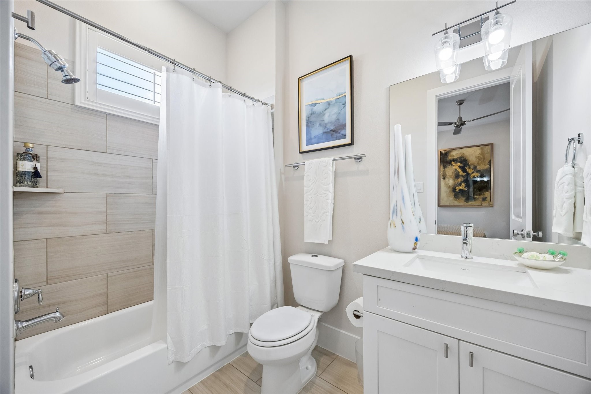 The ensuite bathroom keeps this guest suite feeling polished and comfortable with a single sink vanity, designer lighting, a tub and shower combo with tile surround, all with fresh finishes for everyday ease.