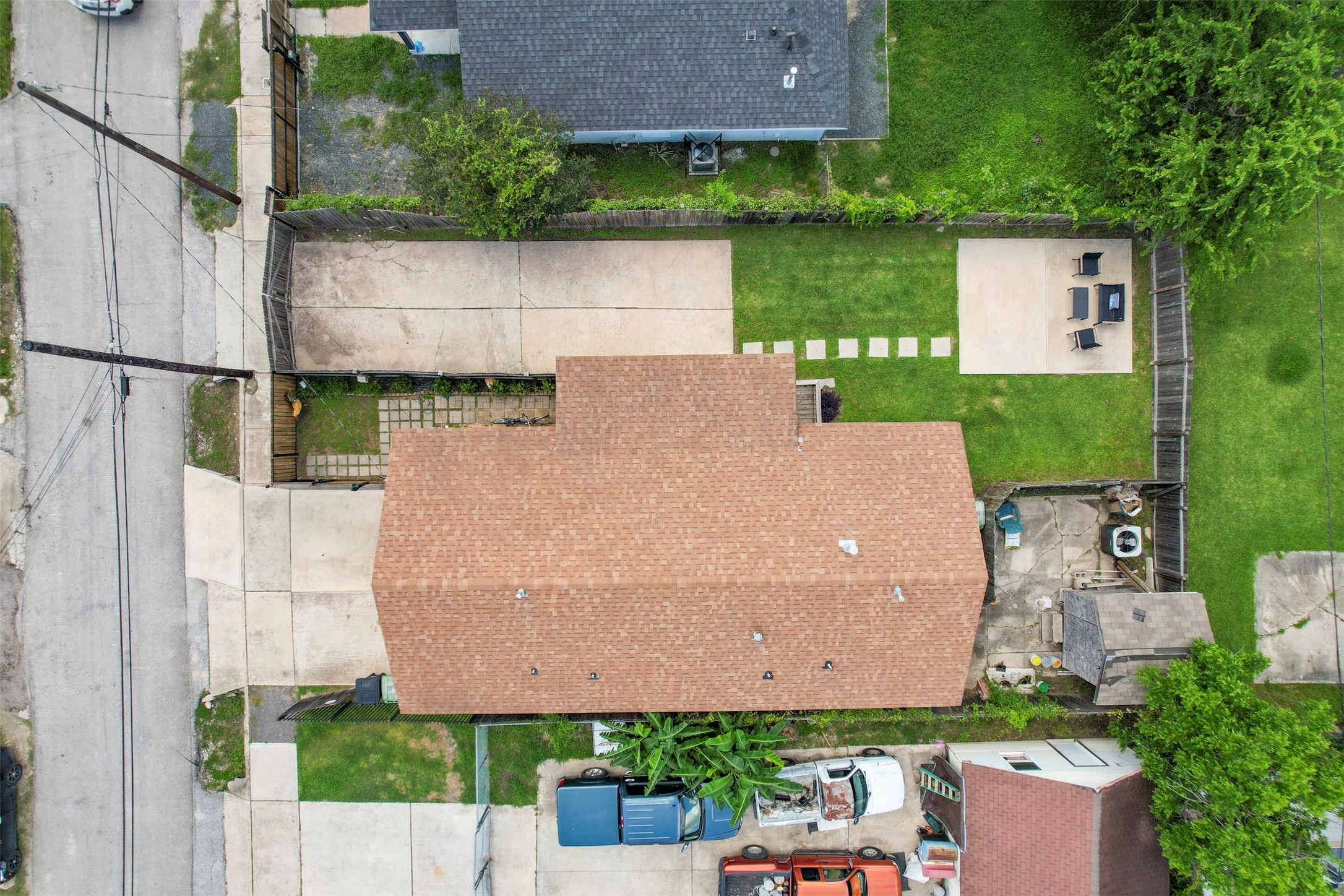Straight-down aerial of the property showing the full footprint, concrete driveway, fully fenced backyard, dedicated patio slab, and stepping stone pathway.