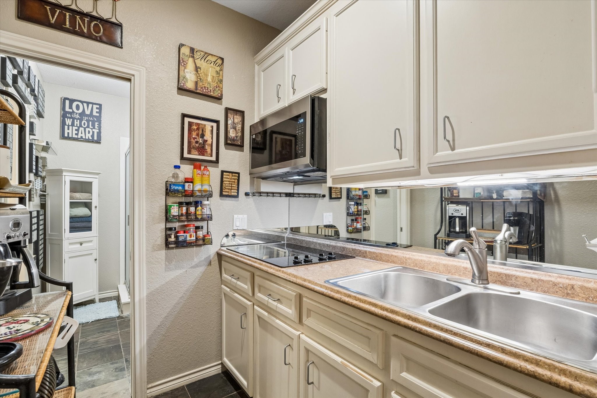 Additional kitchen in the downstairs bedroom/unit featuring cabinetry, sink, cooktop, and built-in microwave. Functional layout supports separate living quarters, ideal for guests, multigenerational use, or rental flexibility.