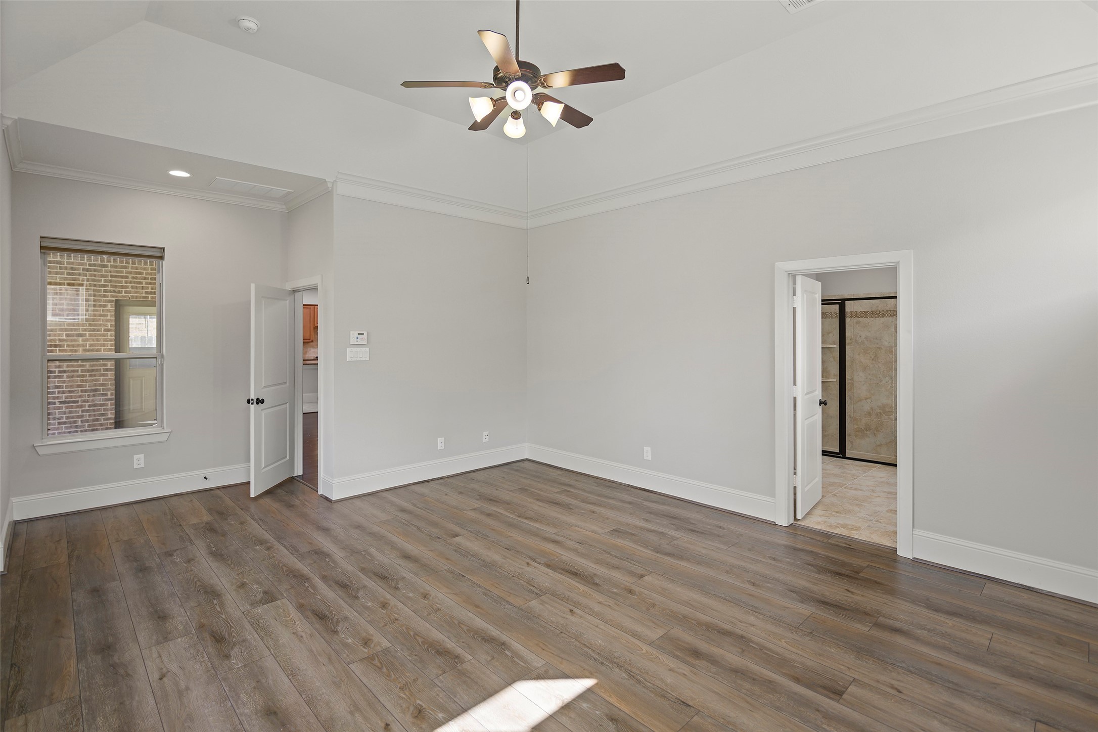 Alternate view of the primary bedroom with luxury plank floor and ensuite bathroom.
