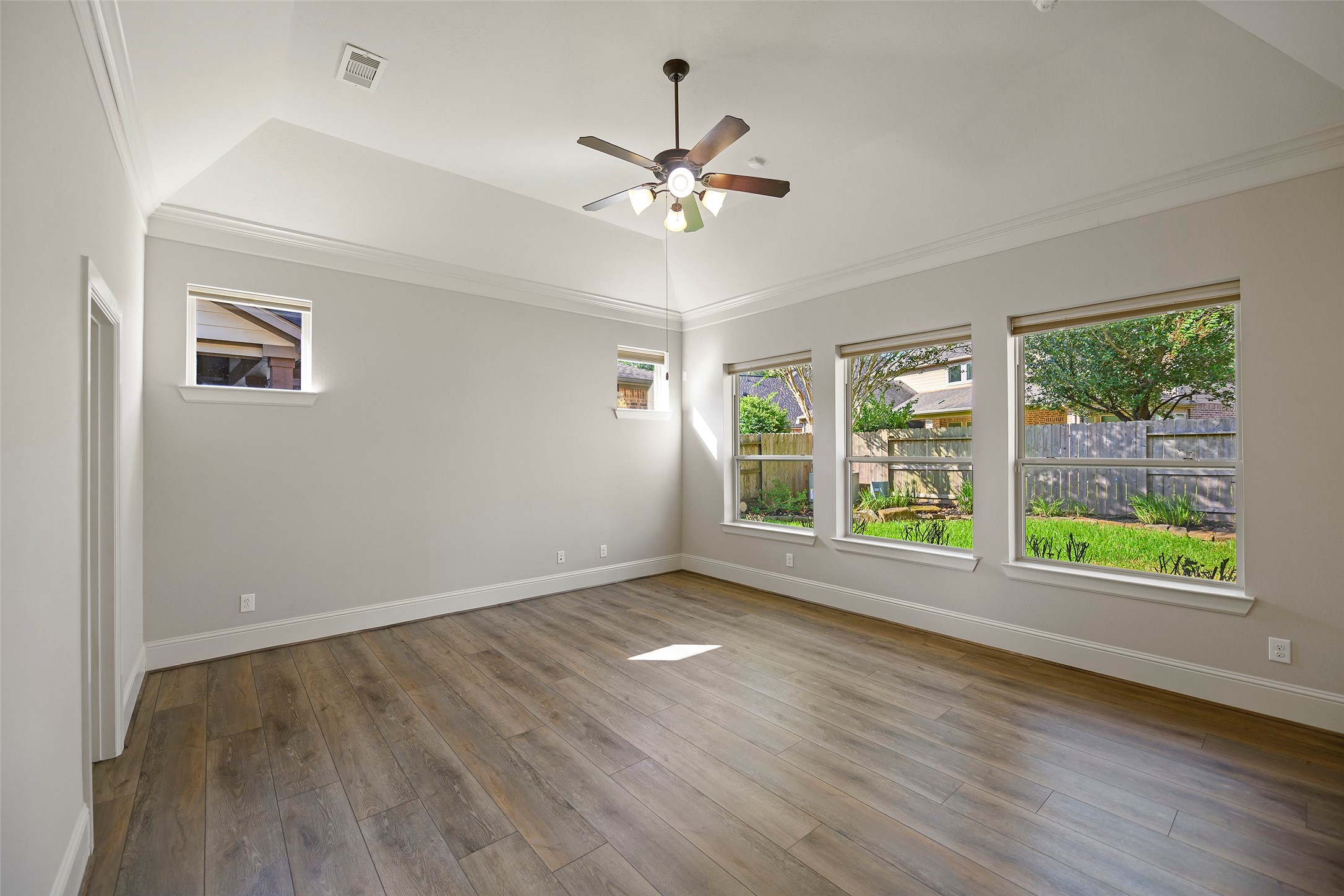 Primary bedroom boasts lots of natural lighting, crown molding and high ceilings.