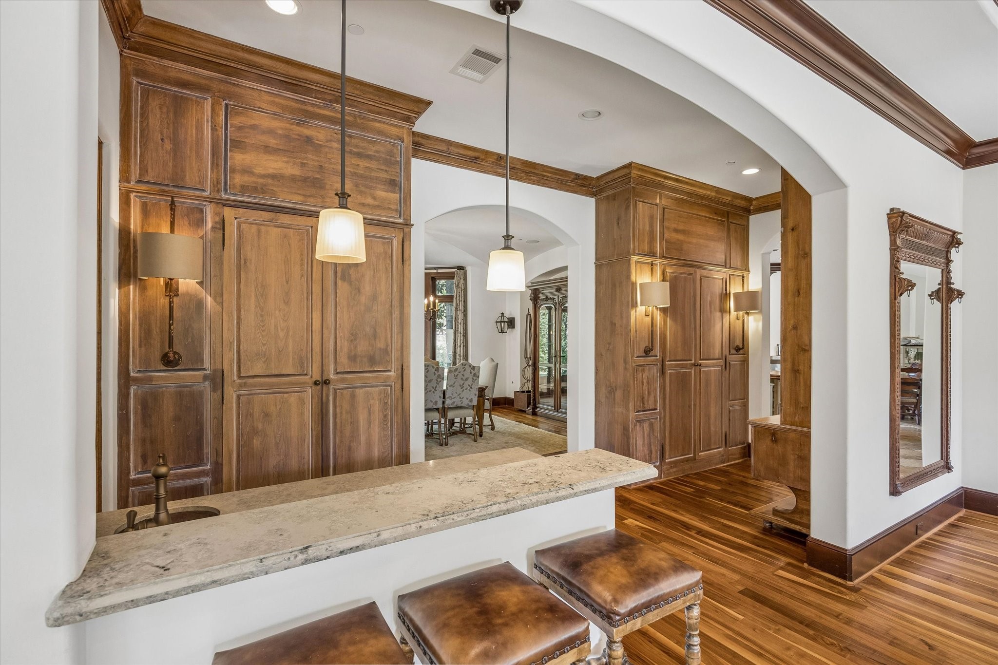 A closer look at the wet bar reveals a generous stone countertop with seating, a built-in sink, and extensive custom wood cabinetry, conveniently positioned between the family and dining rooms.