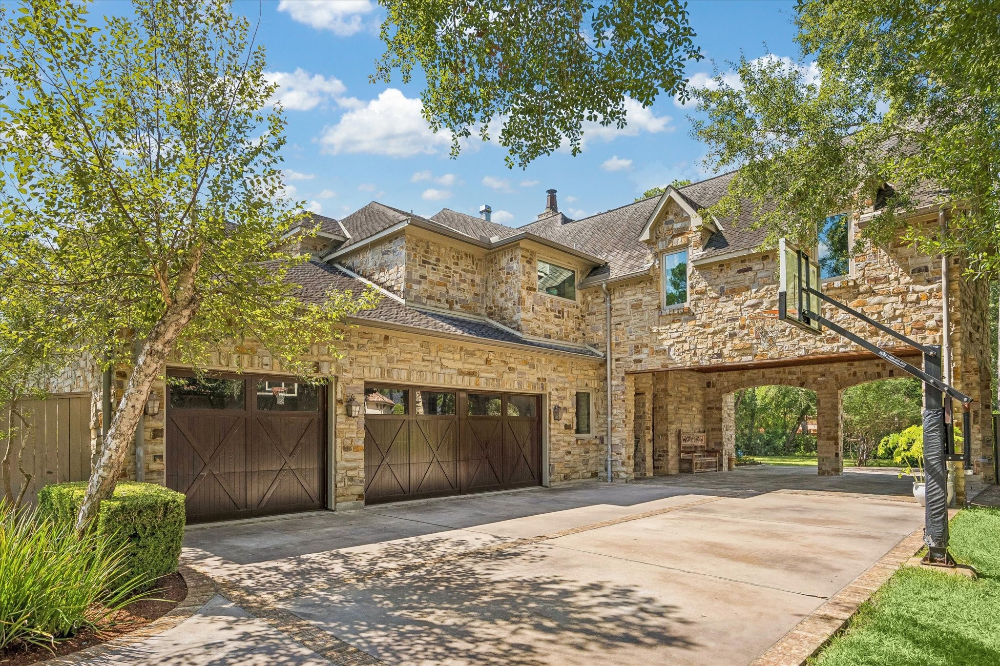 The four-car garage and porte-cochre provide ample parking and convenience, with a spacious driveway and direct gated access to Flintdale.