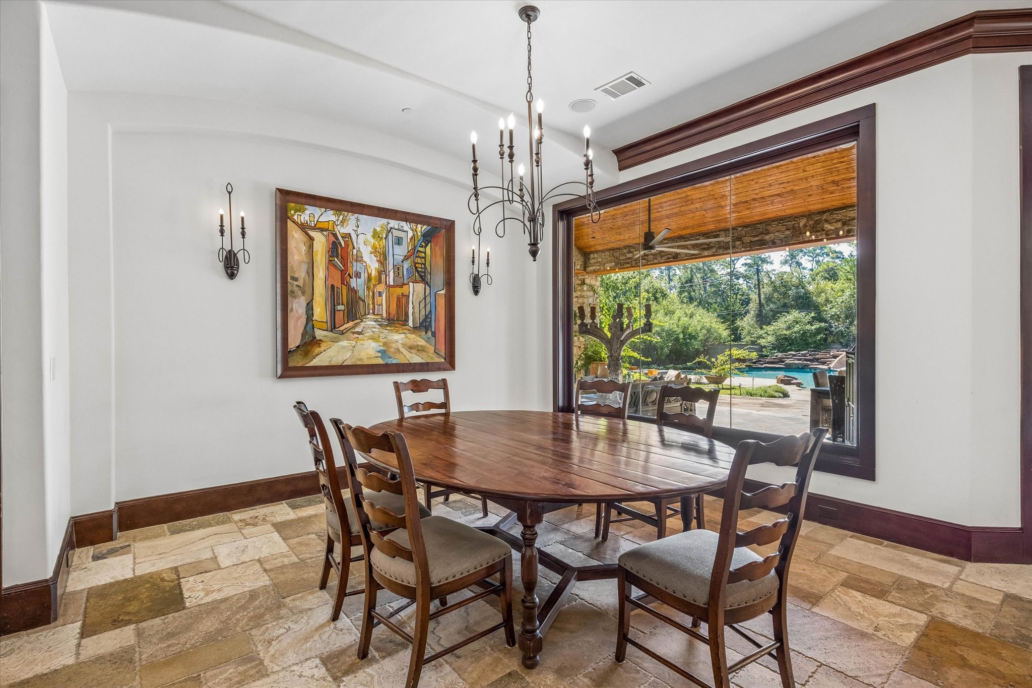 The breakfast room offers a relaxed setting for everyday dining, with subtle ceiling details and a large picture window overlooking the covered patio and resort-style pool.