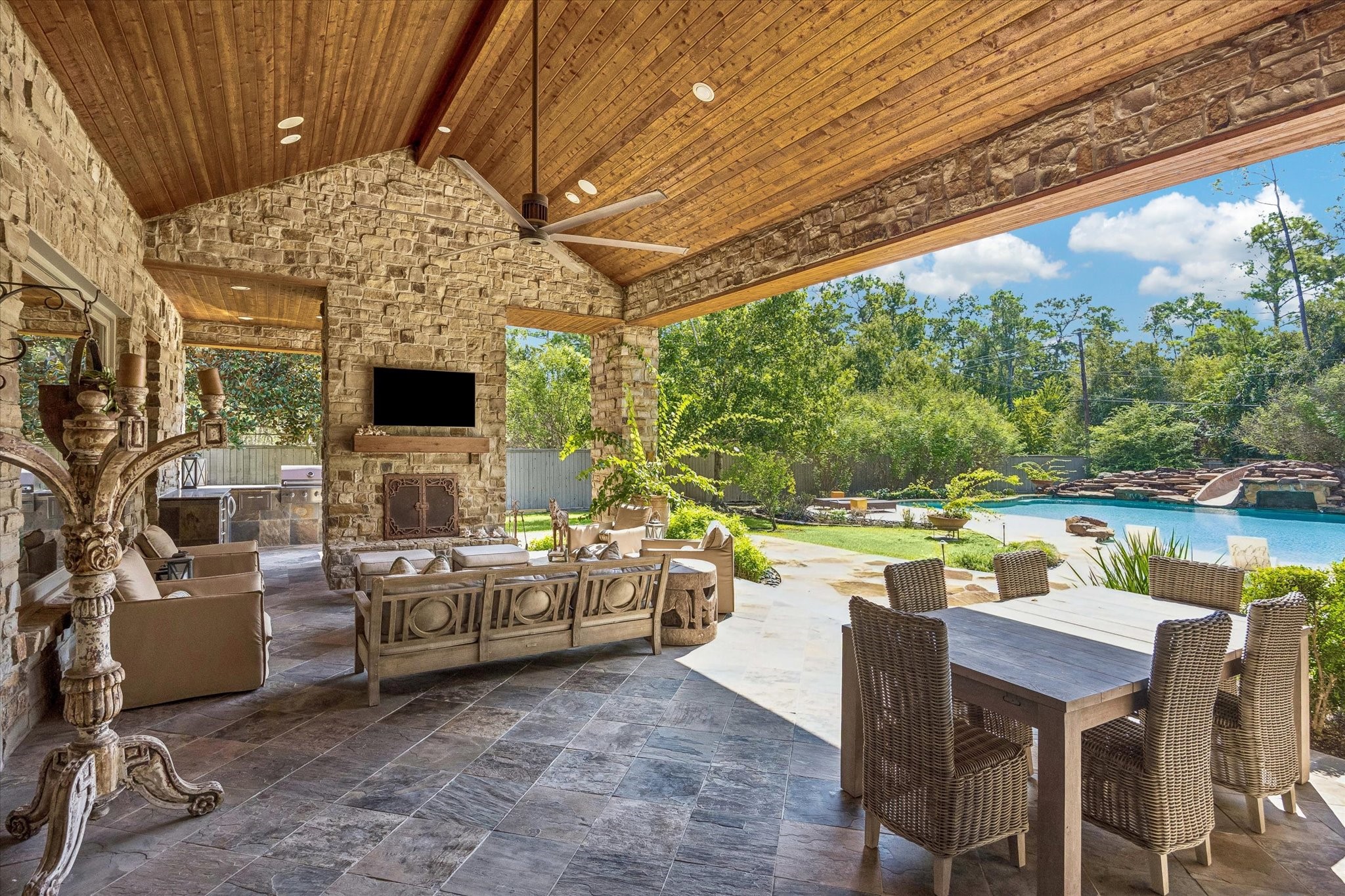 Gather around the outdoor fireplace beneath the vaulted wood ceiling, with a spacious seating area and a fully equipped summer kitchen conveniently located on the opposite side of the fireplace.