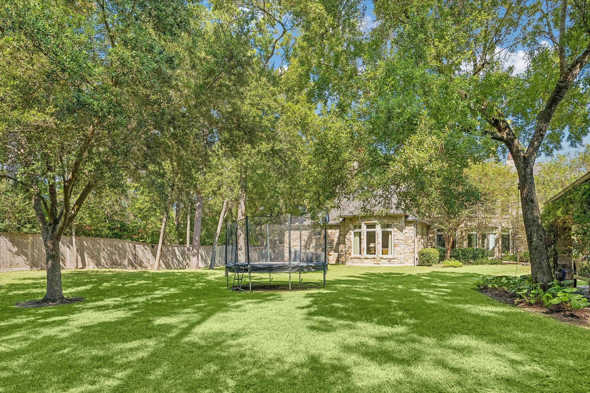 A sprawling backyard offers an expansive lawn shaded by mature trees, creating a peaceful setting with plenty of room for outdoor activities, recreation, and gatherings. The generous green space provides a wonderful complement to the home's impressive outdoor living areas.