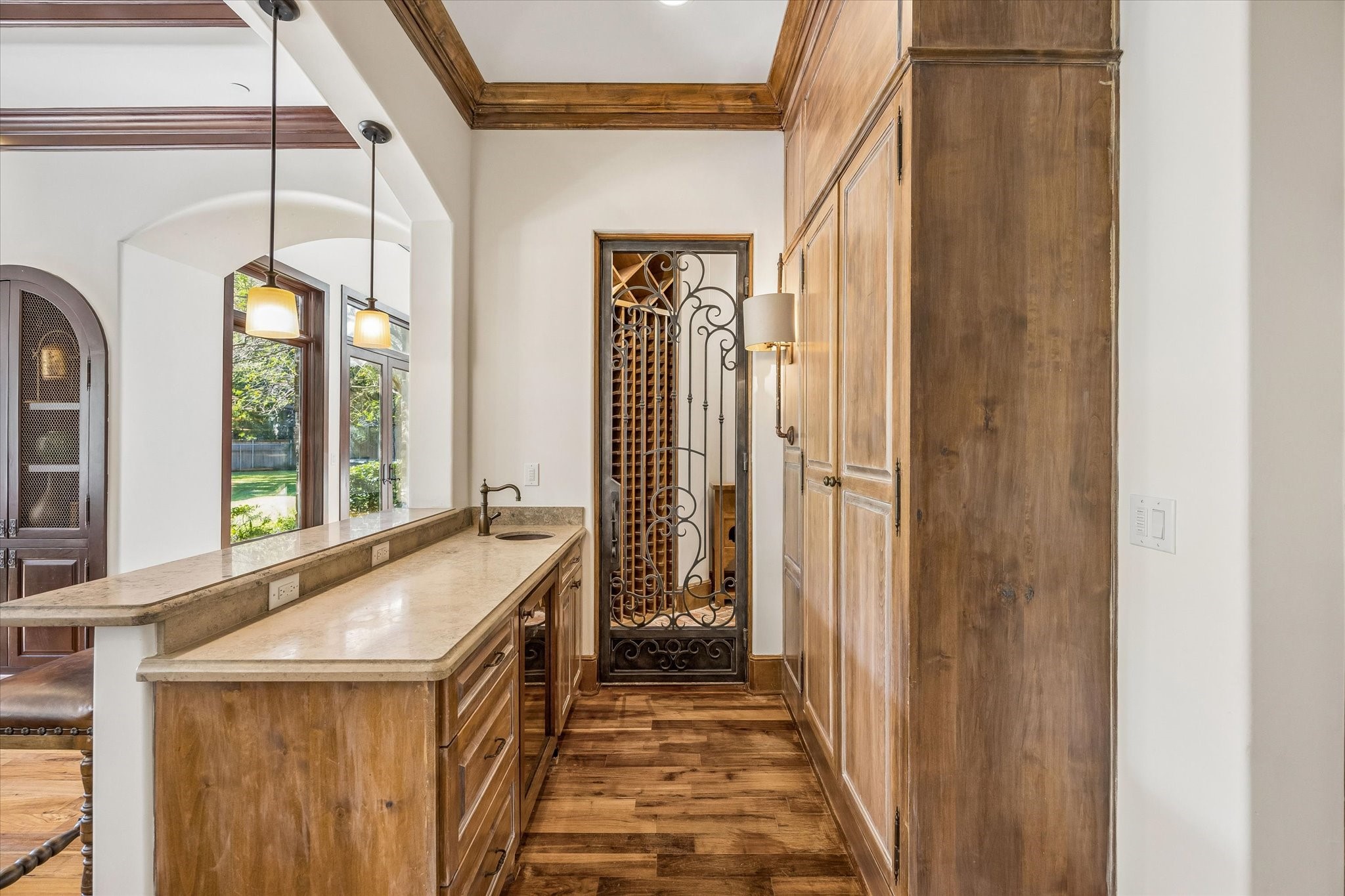 Just off the family room, a thoughtfully designed wet bar offers convenient serving space and direct access to a wine room through an elegant wrought iron door.