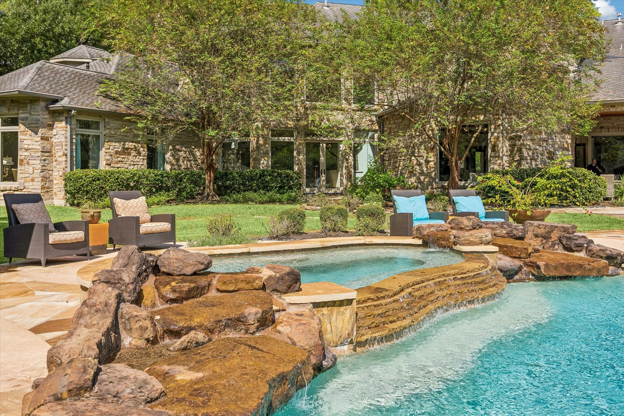 A beautifully integrated spa with natural stone accents and a cascading spillway offers a relaxing retreat overlooking the rear of the residence.