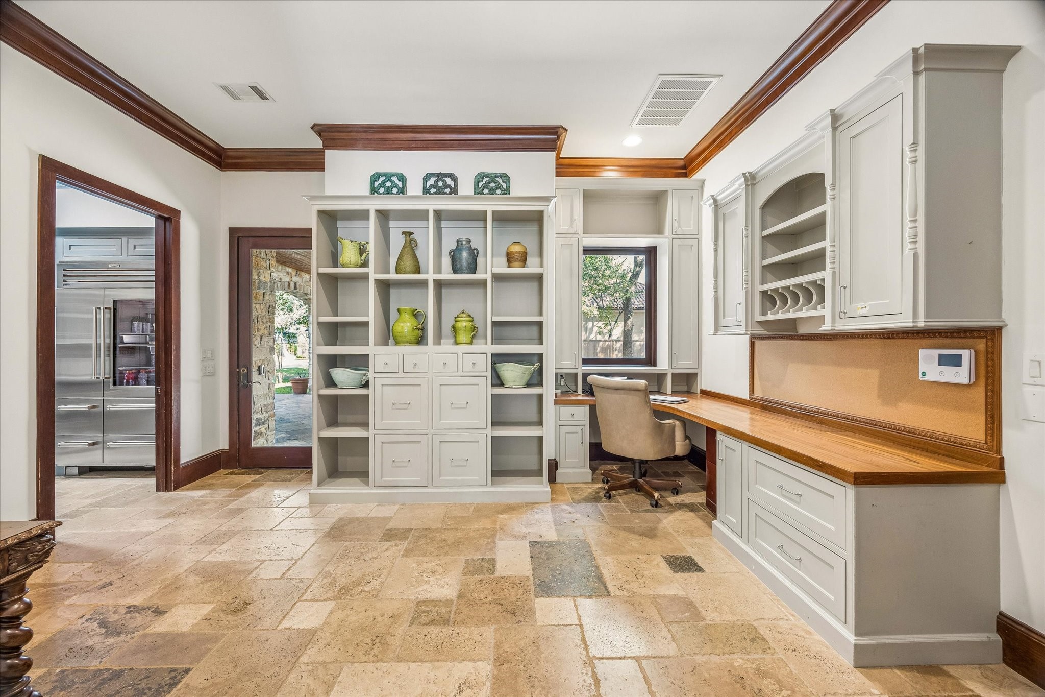 Combining the convenience of a home office and mudroom, this versatile space features built-in desks, custom cabinetry, ample storage, and easy access to the outdoors.