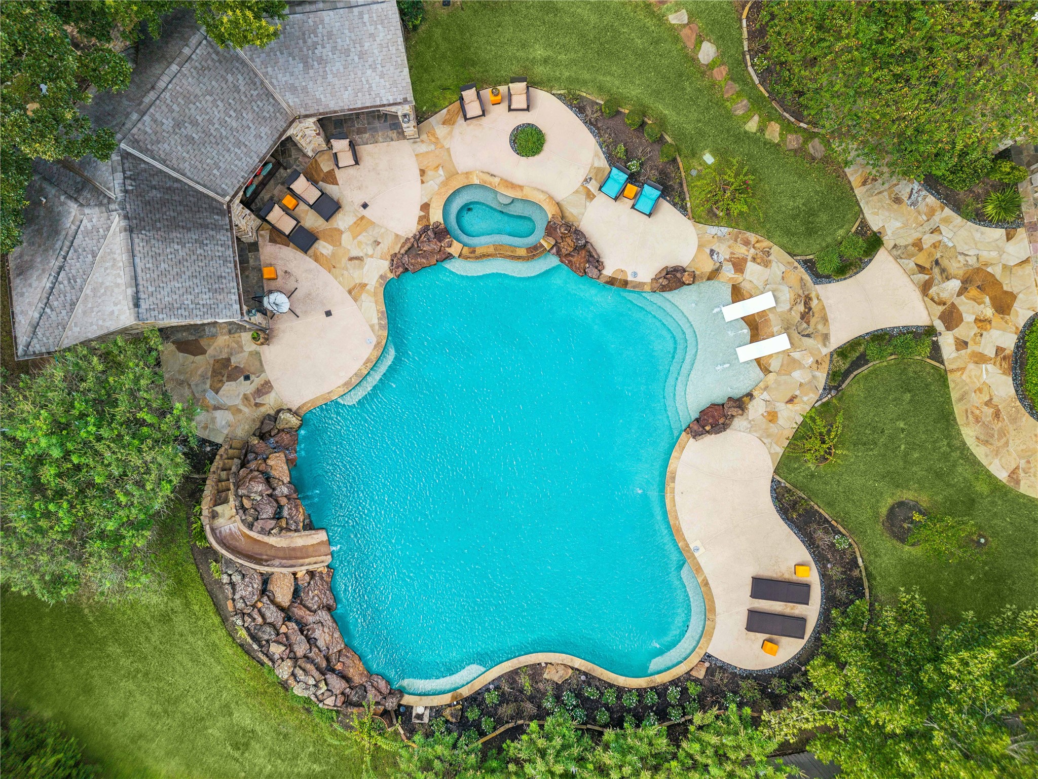 Wow! This spectacular resort-style pool is the centerpiece of the backyard, featuring a custom waterslide, cascading waterfalls, integrated spa, sun shelf, and beautifully designed stone patios connecting to the separate outdoor pavilion.