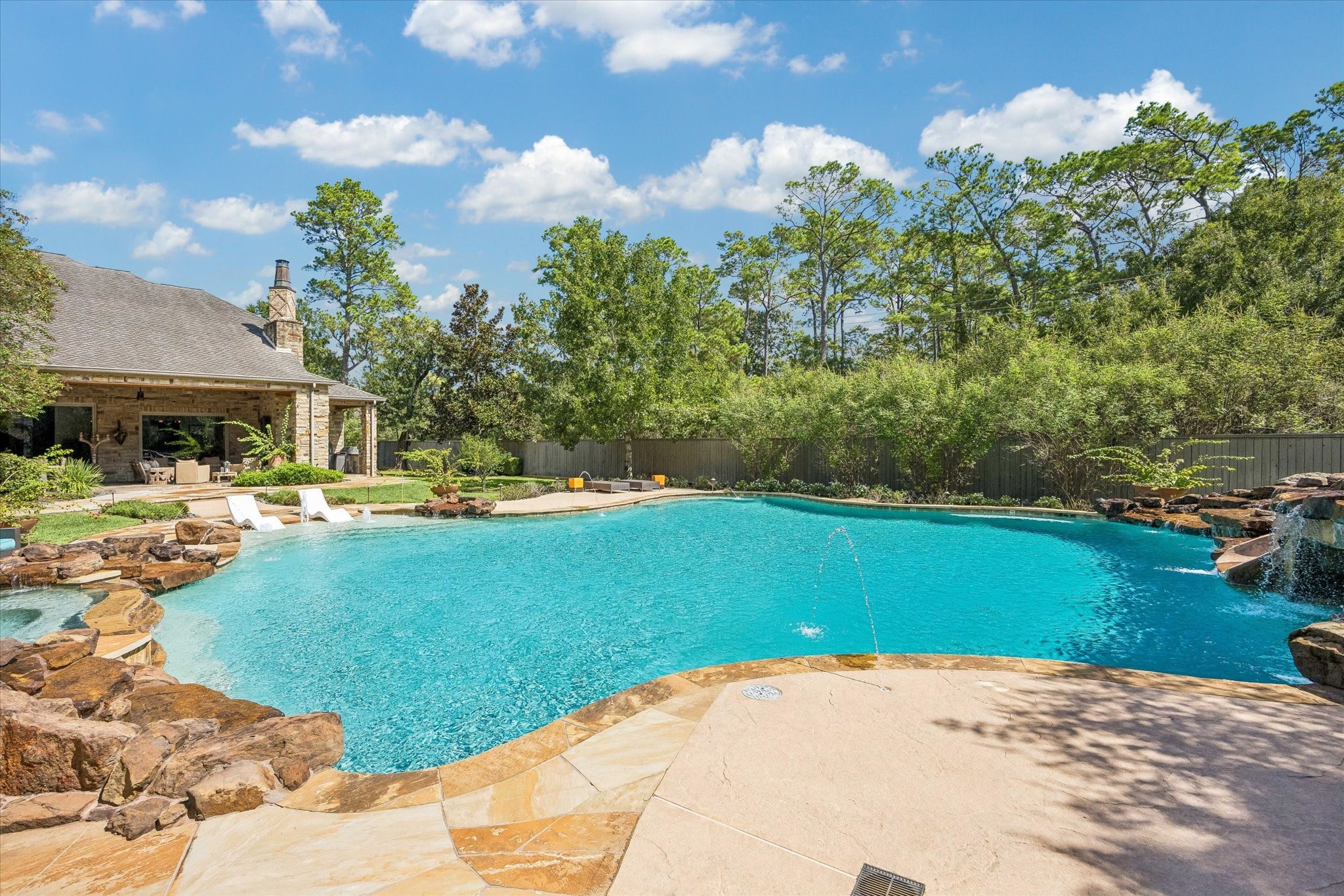 An impressive resort-style pool takes center stage in the backyard, offering generous space for swimming and relaxation with cascading waterfalls, fountains, and expansive surrounding patios.
