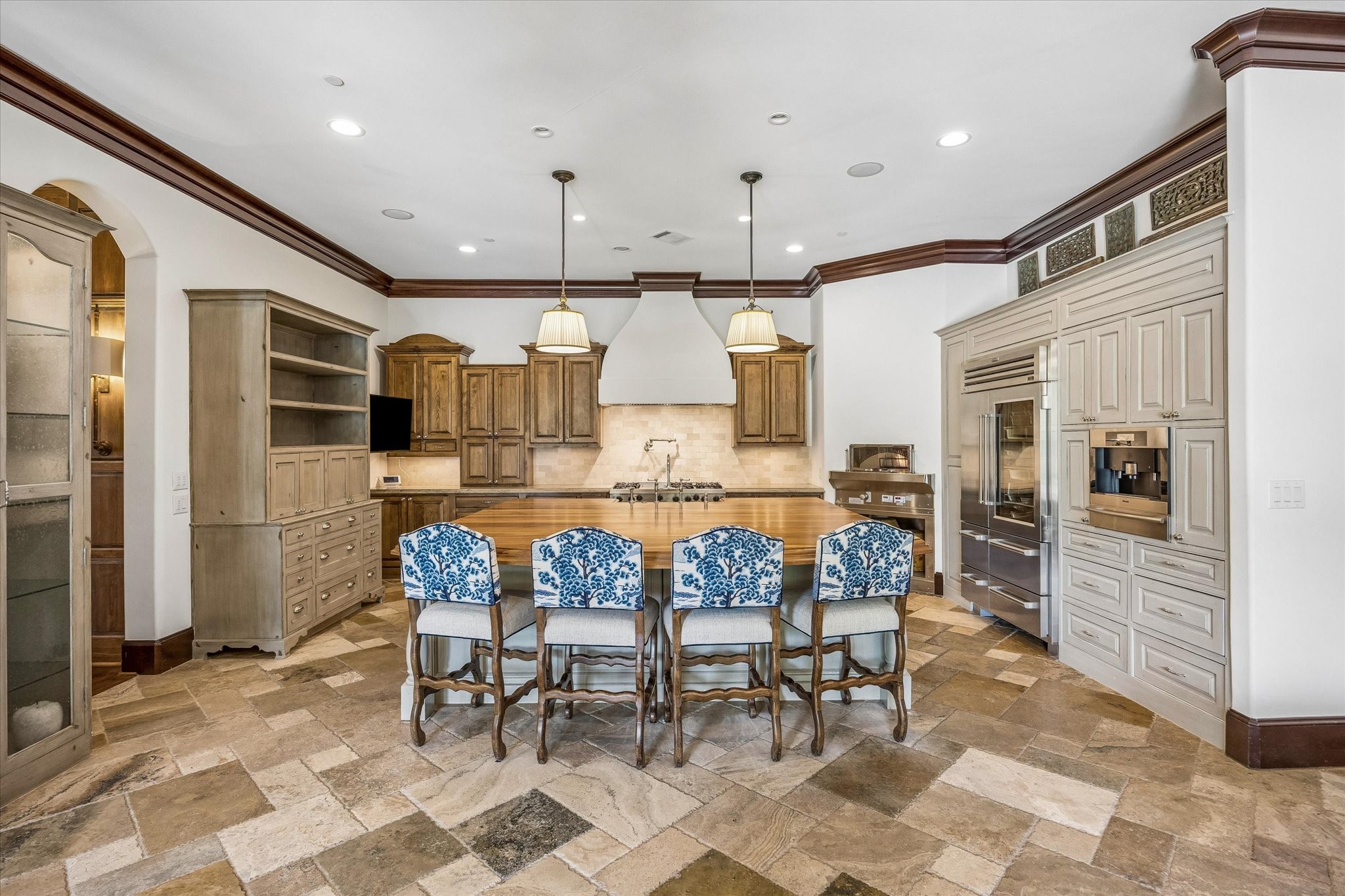 Designed for cooking and gathering, the spacious kitchen features an oversized island with seating, a professional-style range, custom cabinetry, and a full wall of built-in appliances.