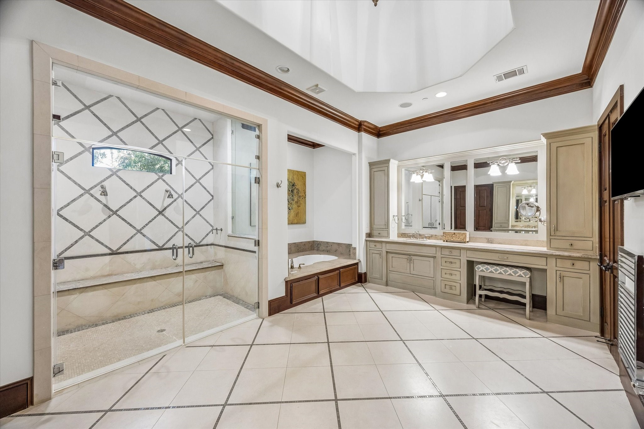 The spacious primary bath offers a spa-like setting with soaring ceilings, a soaking tub, custom cabinetry, a vanity area, and access to two incredible walk-in closets.
