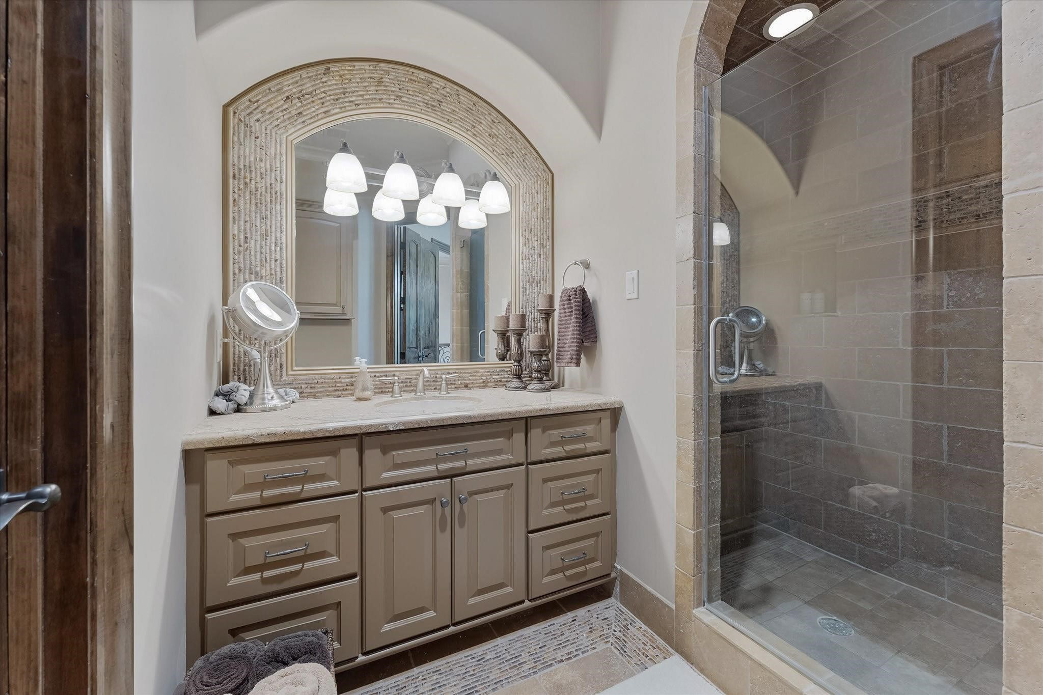Guest bedroom ensuite #1 on the second floor.
Dual Adler wood doors lead to the Ensuite bathroom with custom tile flooring with intricate patterns, a shower with a built-in bench, and a Granite countertop vanity with Custom framed mirror. Walk-in Closet with built-in and door jamb Light Switch.