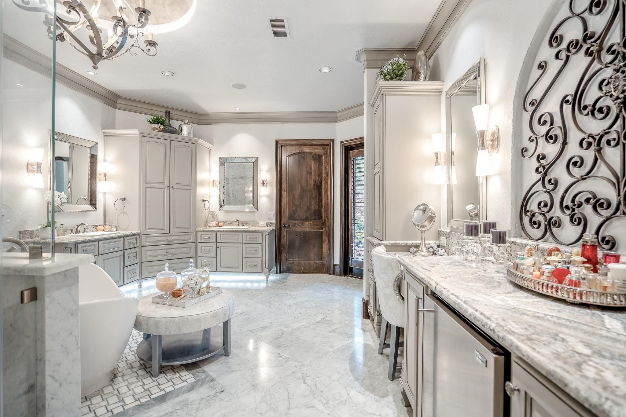 Alpine granite countertops, separate vanities with dual sinks and built-in cabinetry, a separate makeup vanity.The room boasts under-vanity lighting, Venetian plaster dome ceiling with a custom chandelier, and recessed LED lighting., subzero beverage fridge. Additional features include custom framed mirrors, crown molding, silver wallmounted sconces, and a water closet with a Toto Neorest smart toilet and bidet.