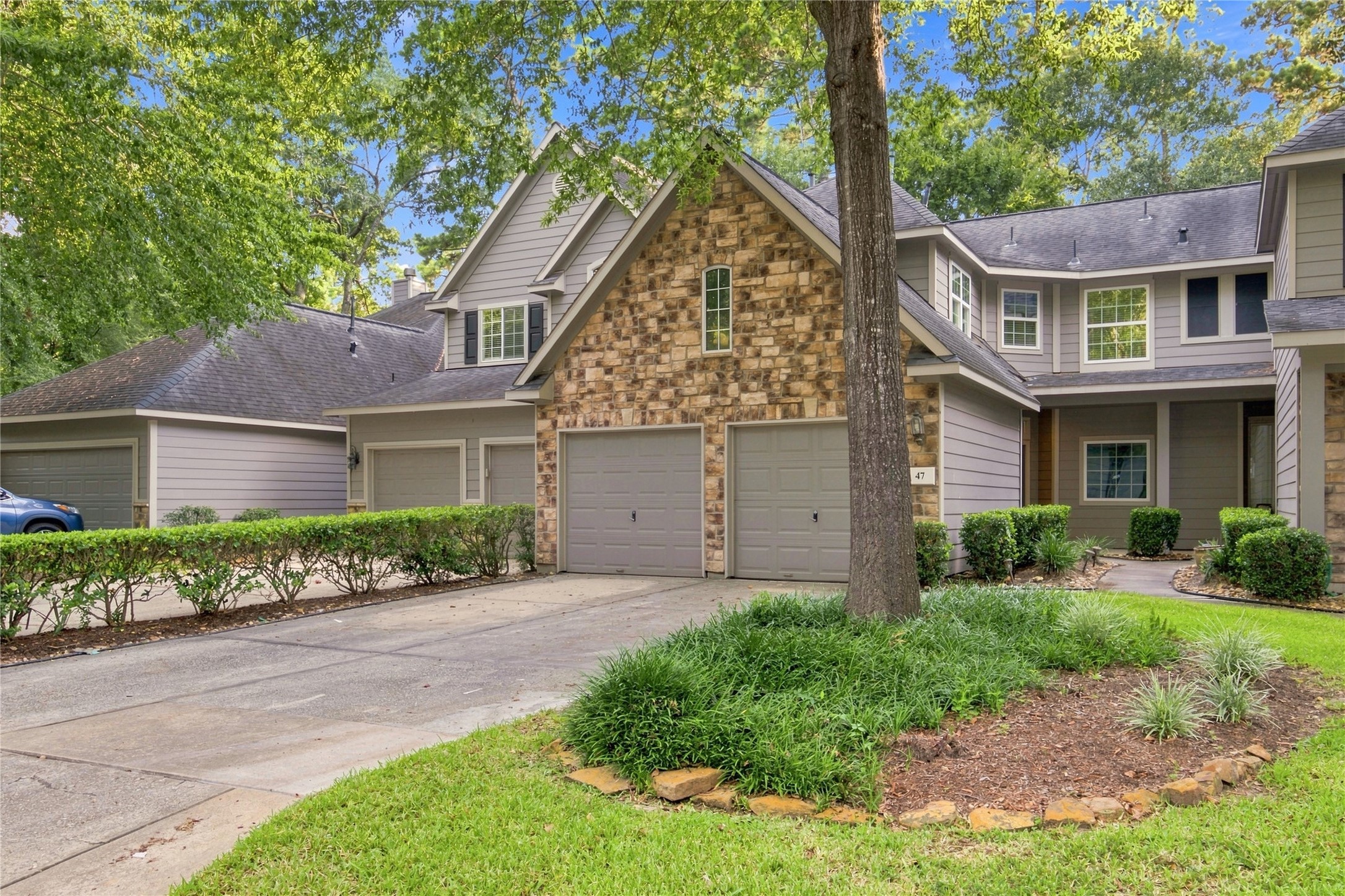Stone-accented exterior with mature trees and an attached two-car garage.