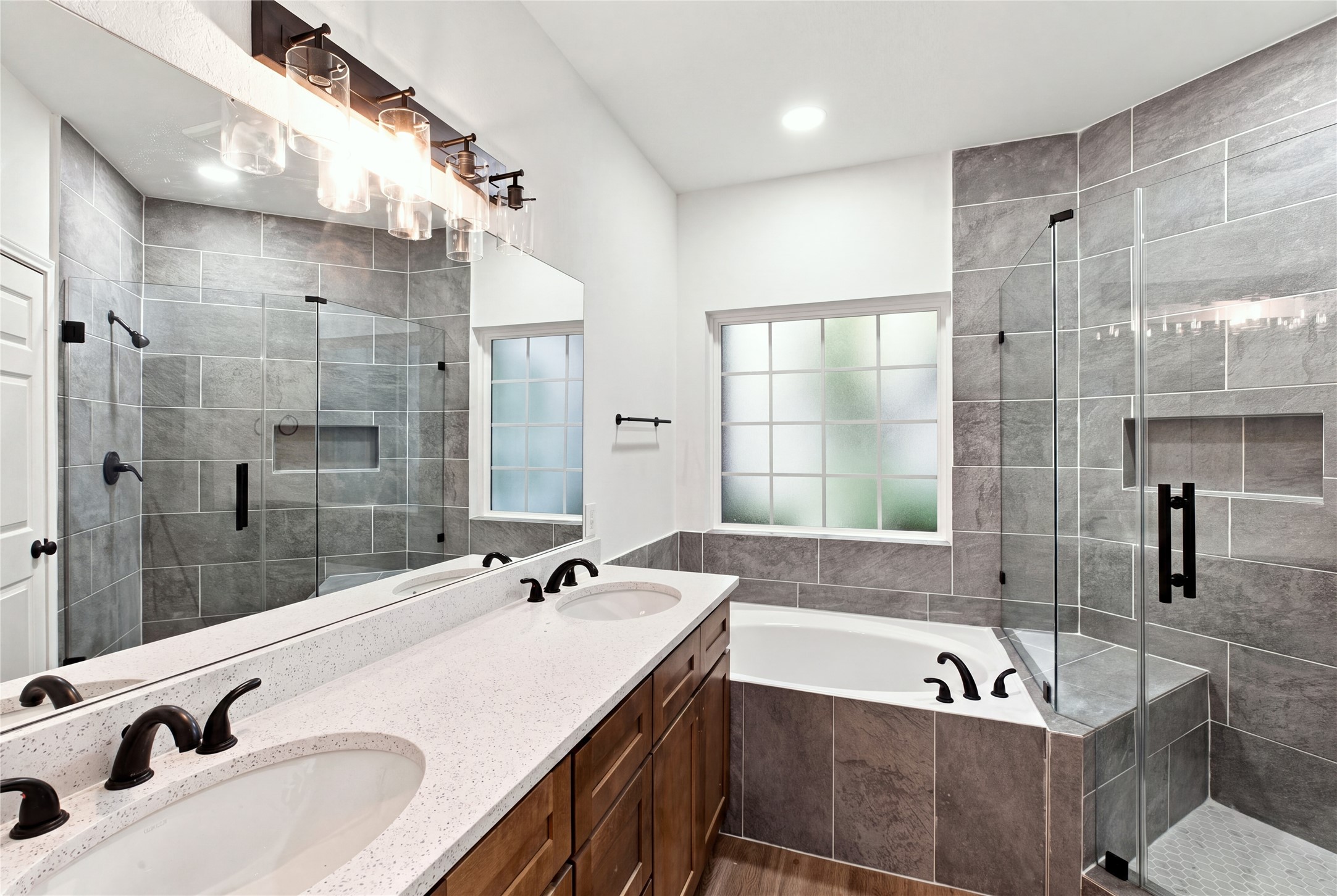 Updated primary en-suite with dual sinks, a soaking tub, frameless glass shower and modern black fixtures.