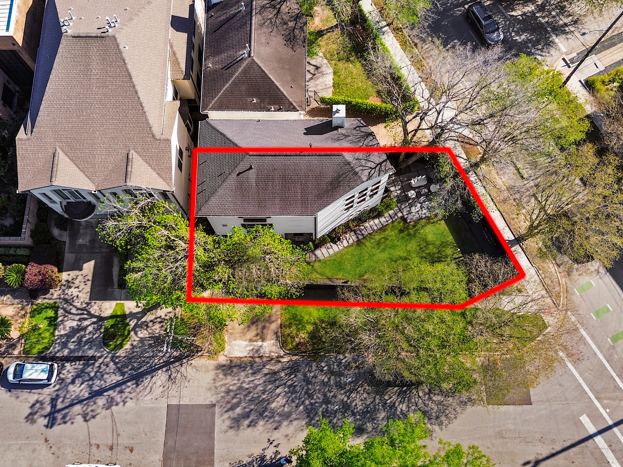 This stunning aerial view captures a charming home nestled on a spacious, lush corner lot, perfectly blending urban convenience with serene privacy.