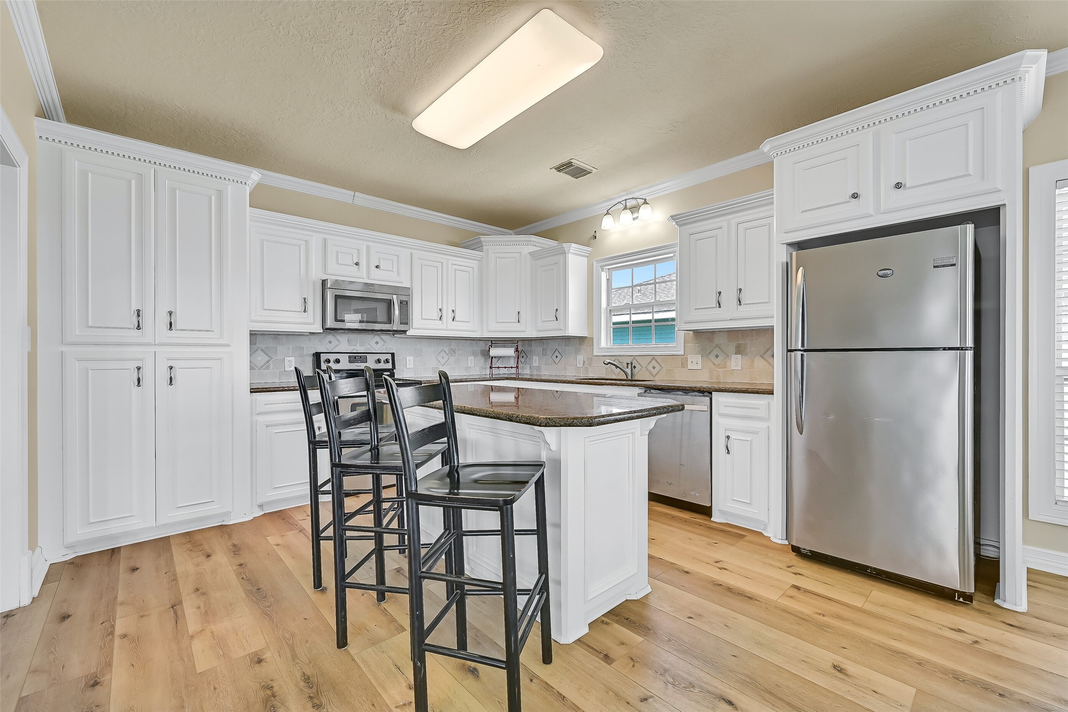 The open kitchen features granite countertops and  stainless steel appliances.