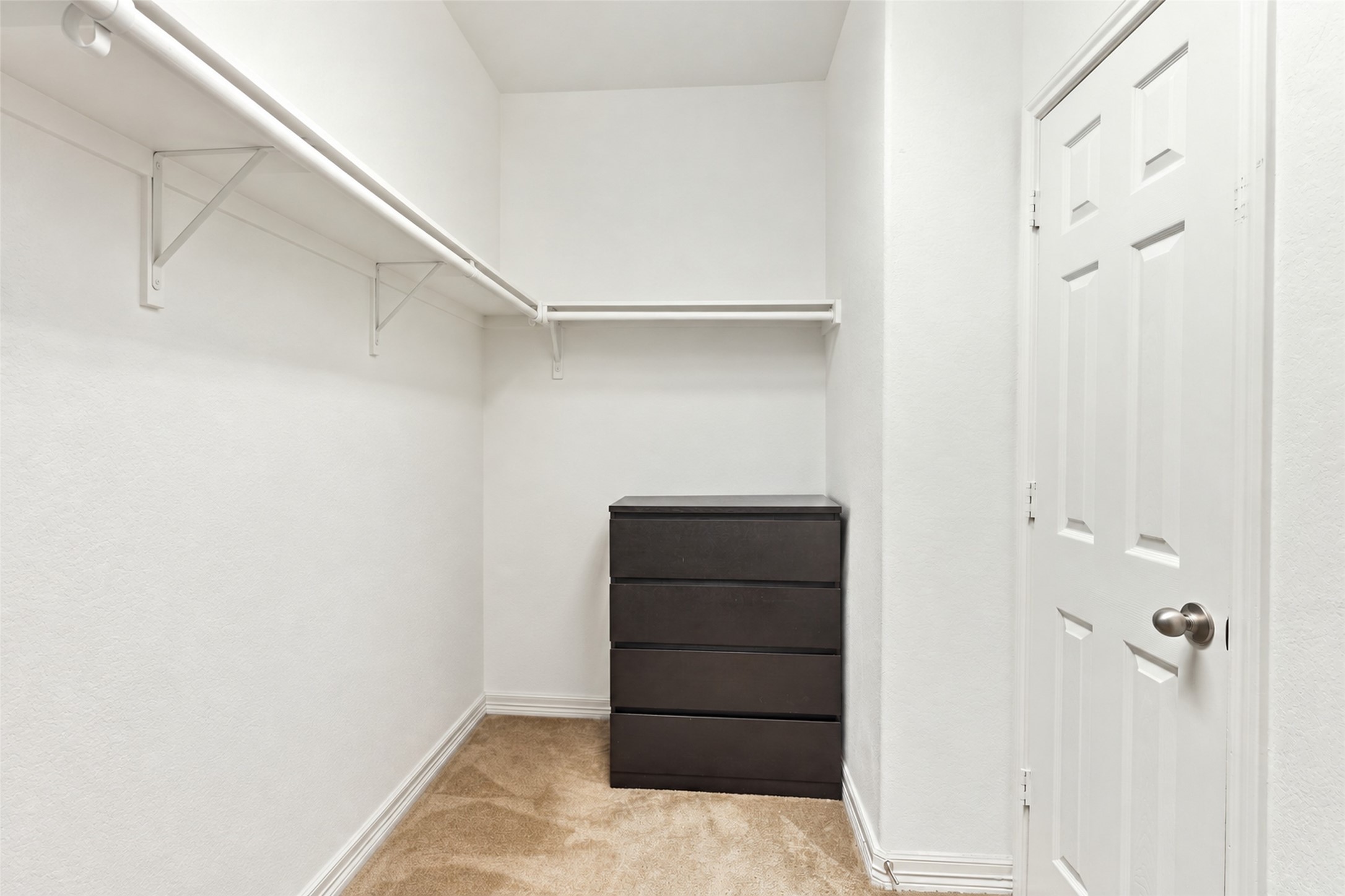 Walk-in closet with wraparound shelving and hanging rods.