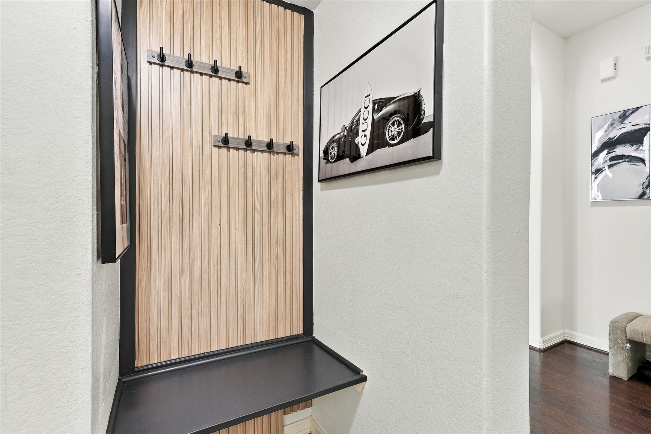 Entry nook with wood accent paneling, coat hooks, and a built-in bench.