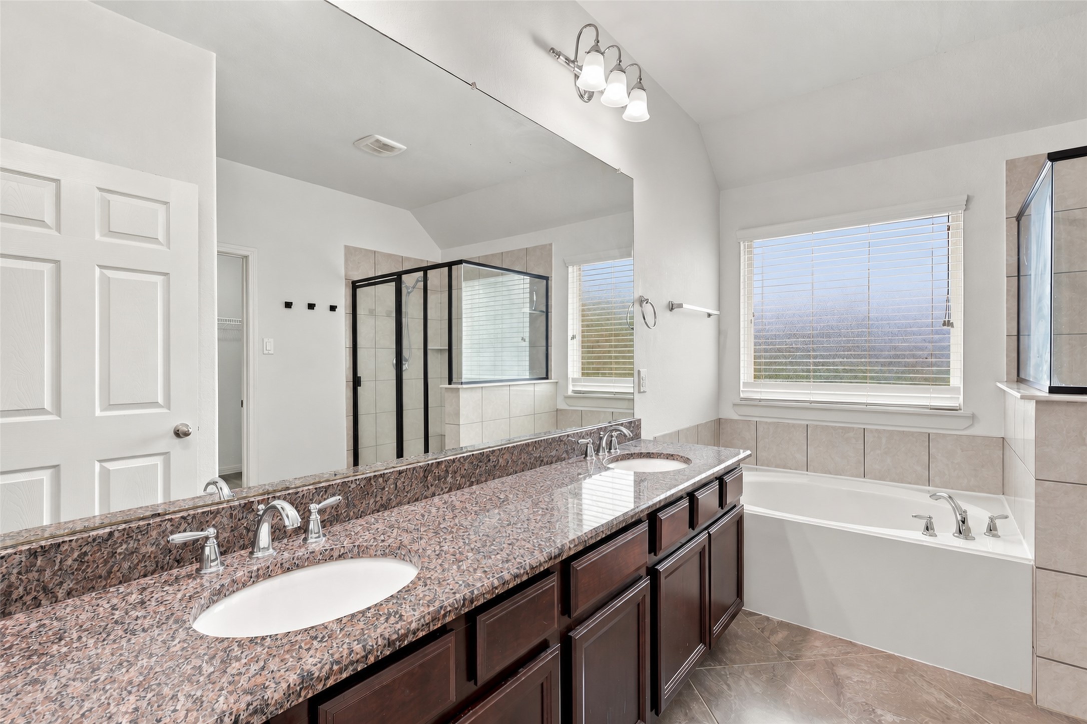 Primary bathroom with dual sinks, granite countertops, and a separate soaking tub.