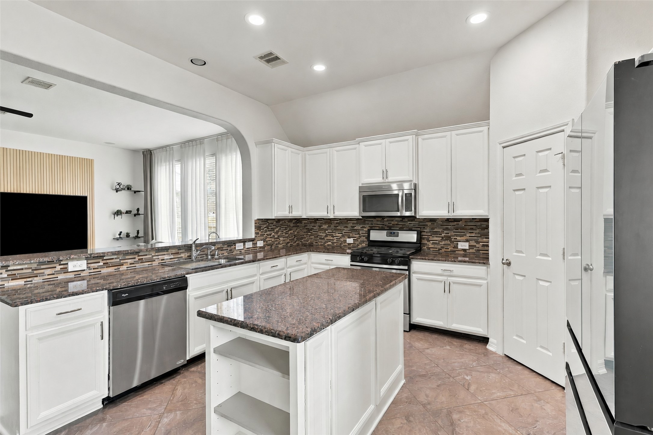 Alternate kitchen view highlighting the gas range, generous counter space, and connection to the living room.