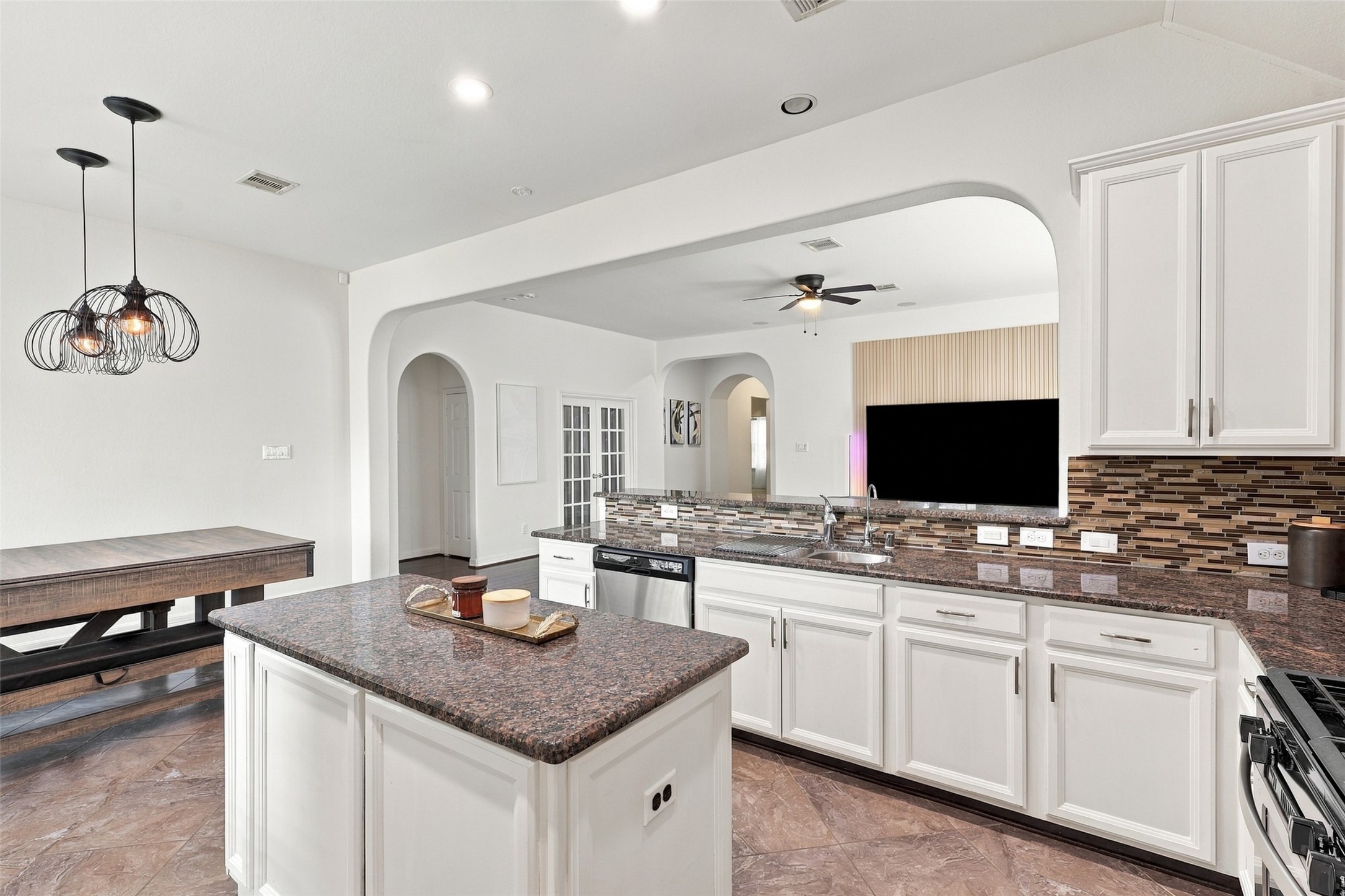 Kitchen island and sink area overlooking the living room through a wide arched opening.