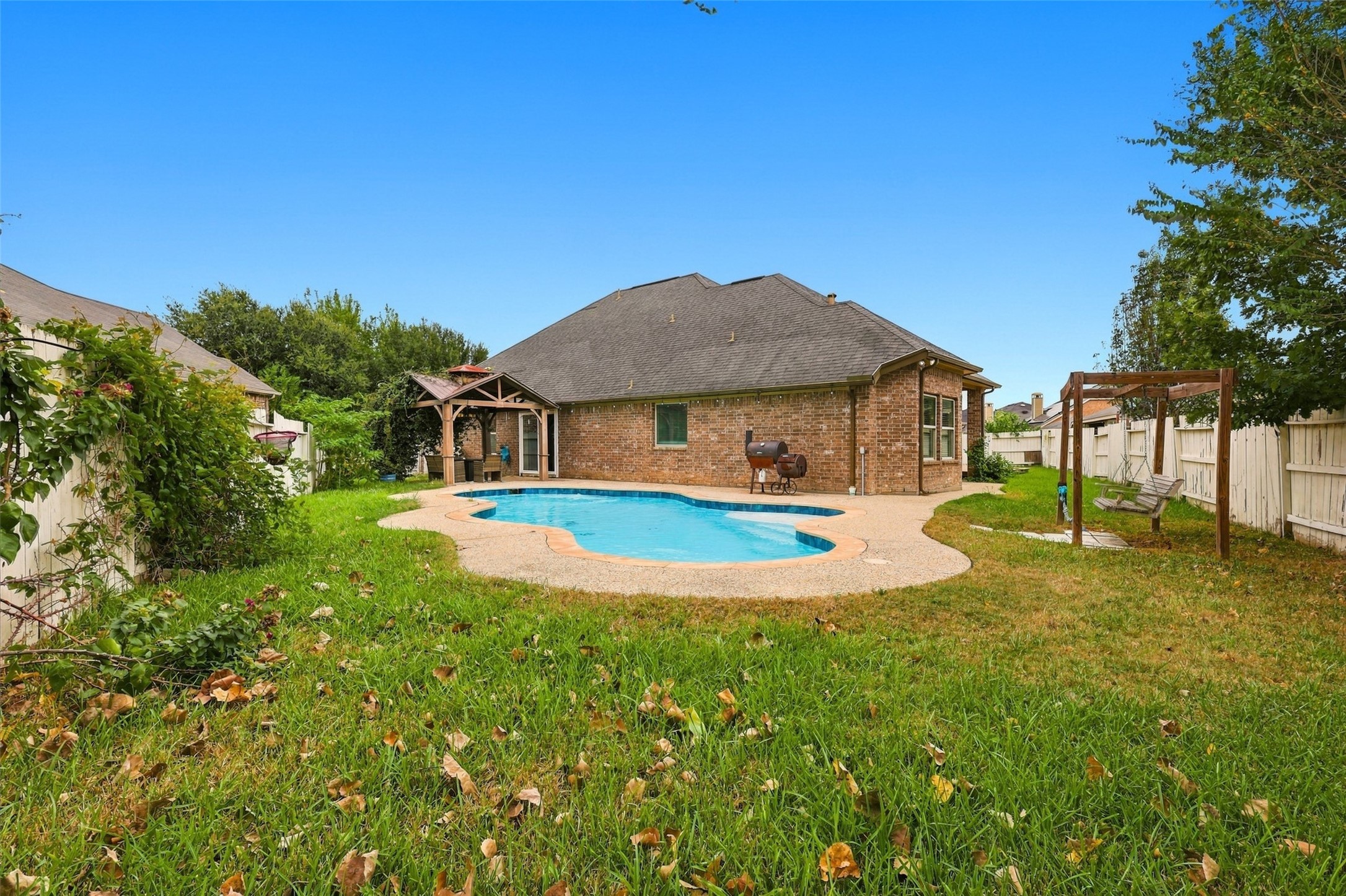 Wide backyard view showcasing the pool, gazebo, lawn, and rear exterior.