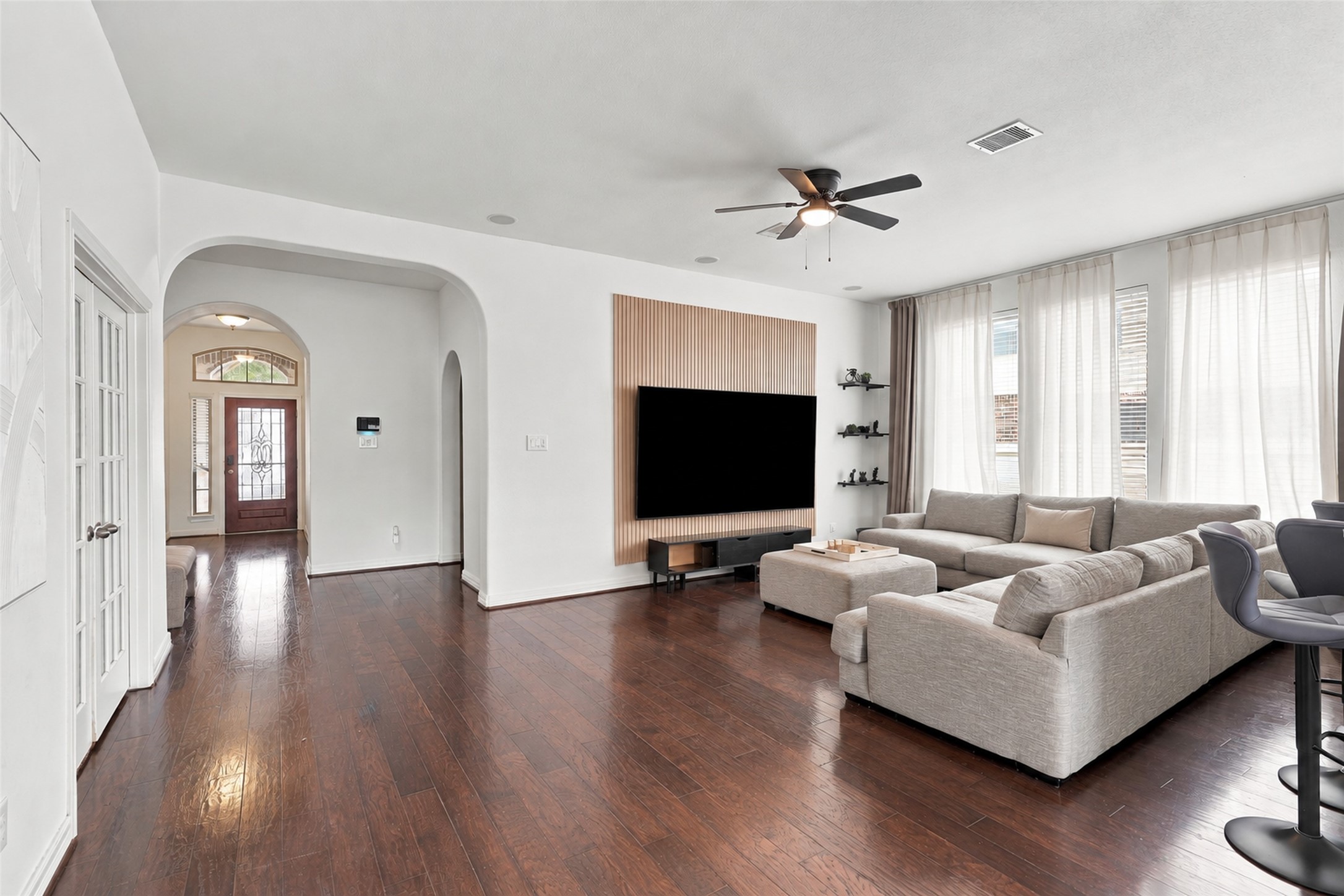 Living area with wood flooring, a slatted accent wall, and views toward the front entry. Living area with wood flooring, a slatted accent wall, and views toward the front entry.