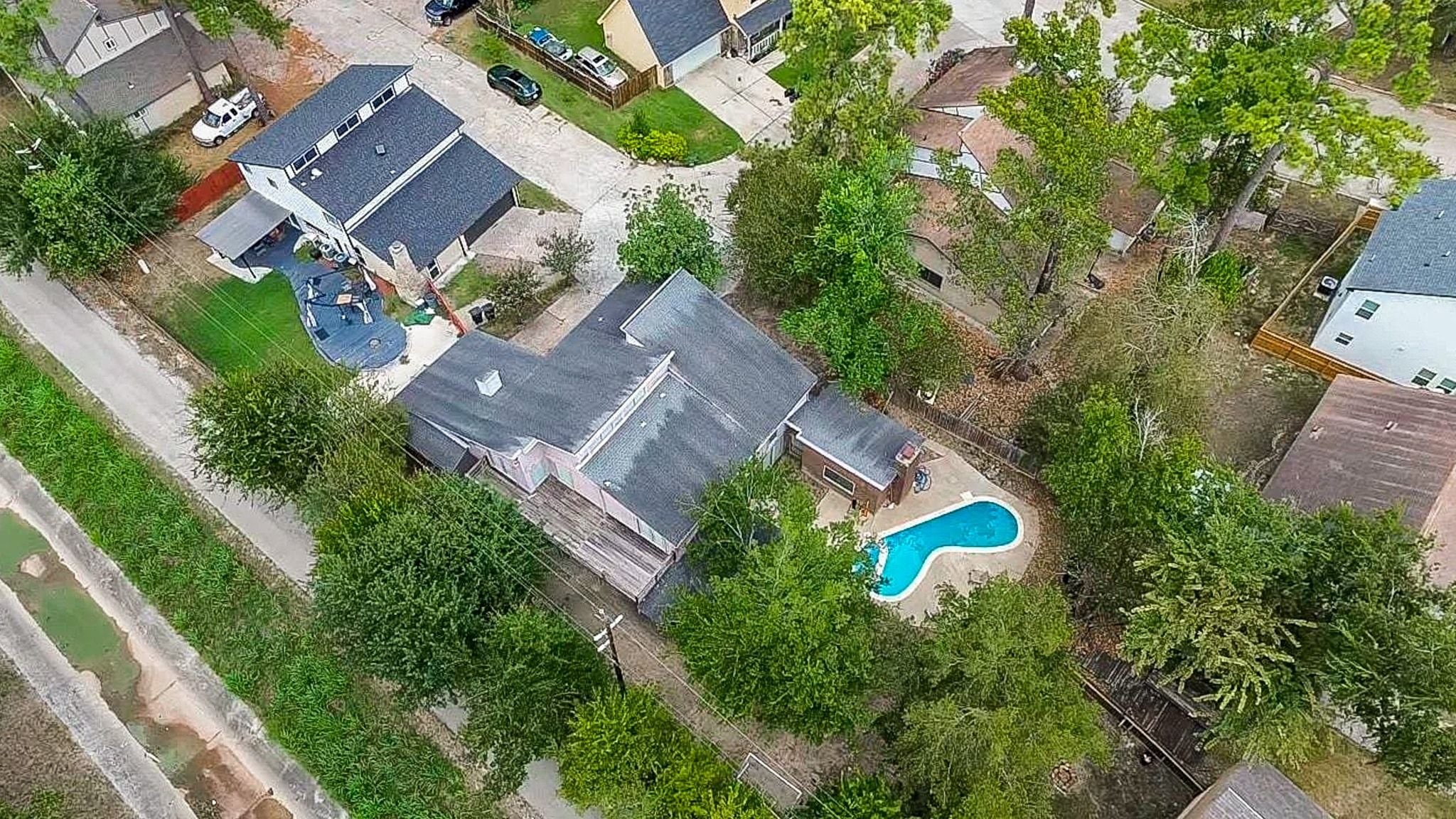 Aerial view showcasing the tree-shaded backyard with pool and patio, fenced yard, and the homes placementon the neighborhoods second-largest lot (per seller).