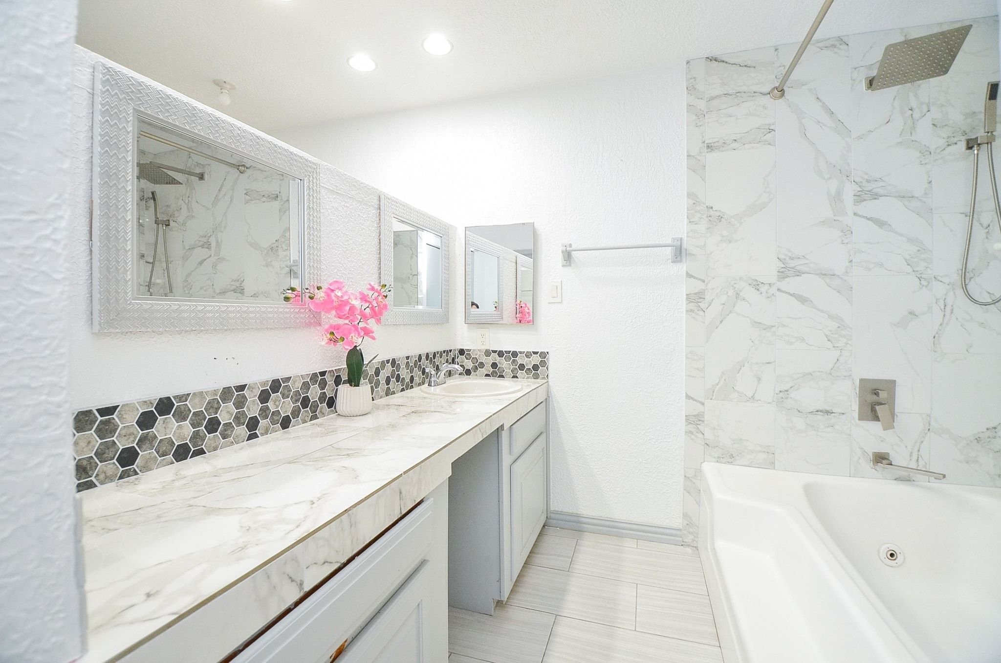 Step into this primary en-suite bath. It features a vanity mirror, shower/tub combination, gorgeous and durable tile flooring, and beautiful backsplash to compliment the countertops.