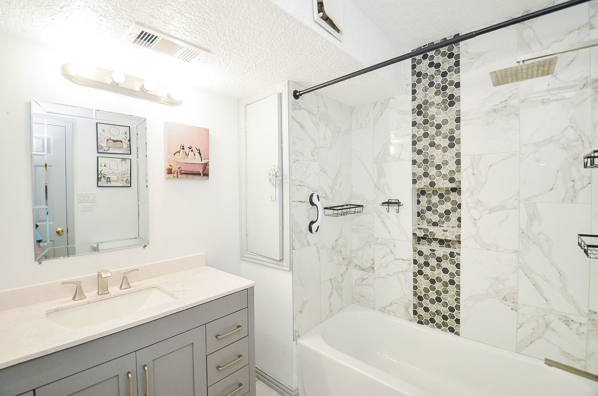 Discover this lovely styled en-suite bathroom. Take a look at the gorgeous shower wall and shower/tub combination and a spacious countertop with beautiful cabinetry to match.