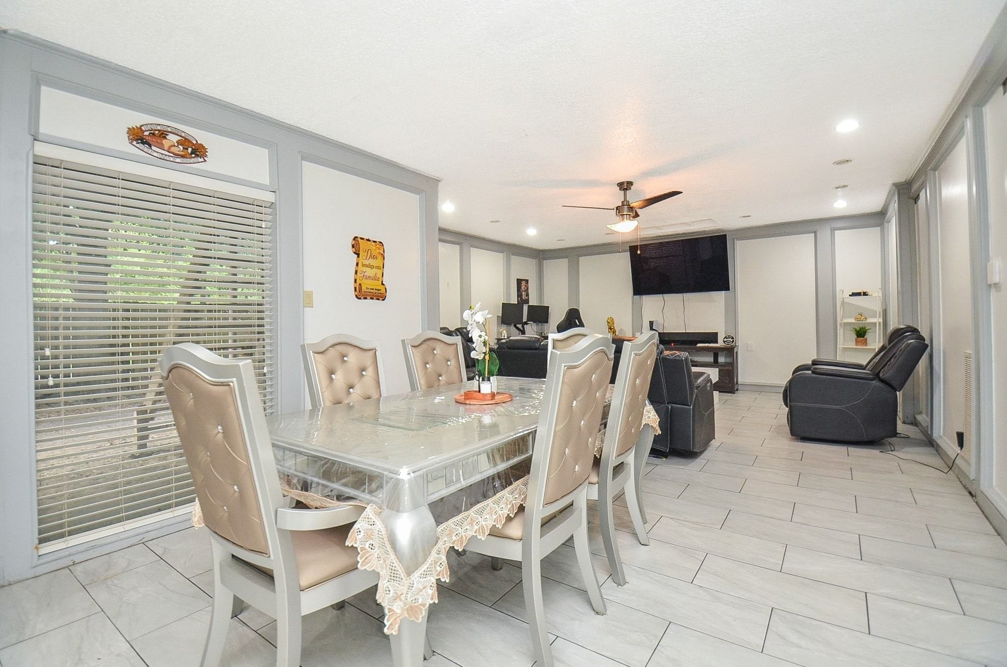 Step into this spacious open-concept dining and living area with modern tile flooring, recessed lighting, and accent wall molding detail!
