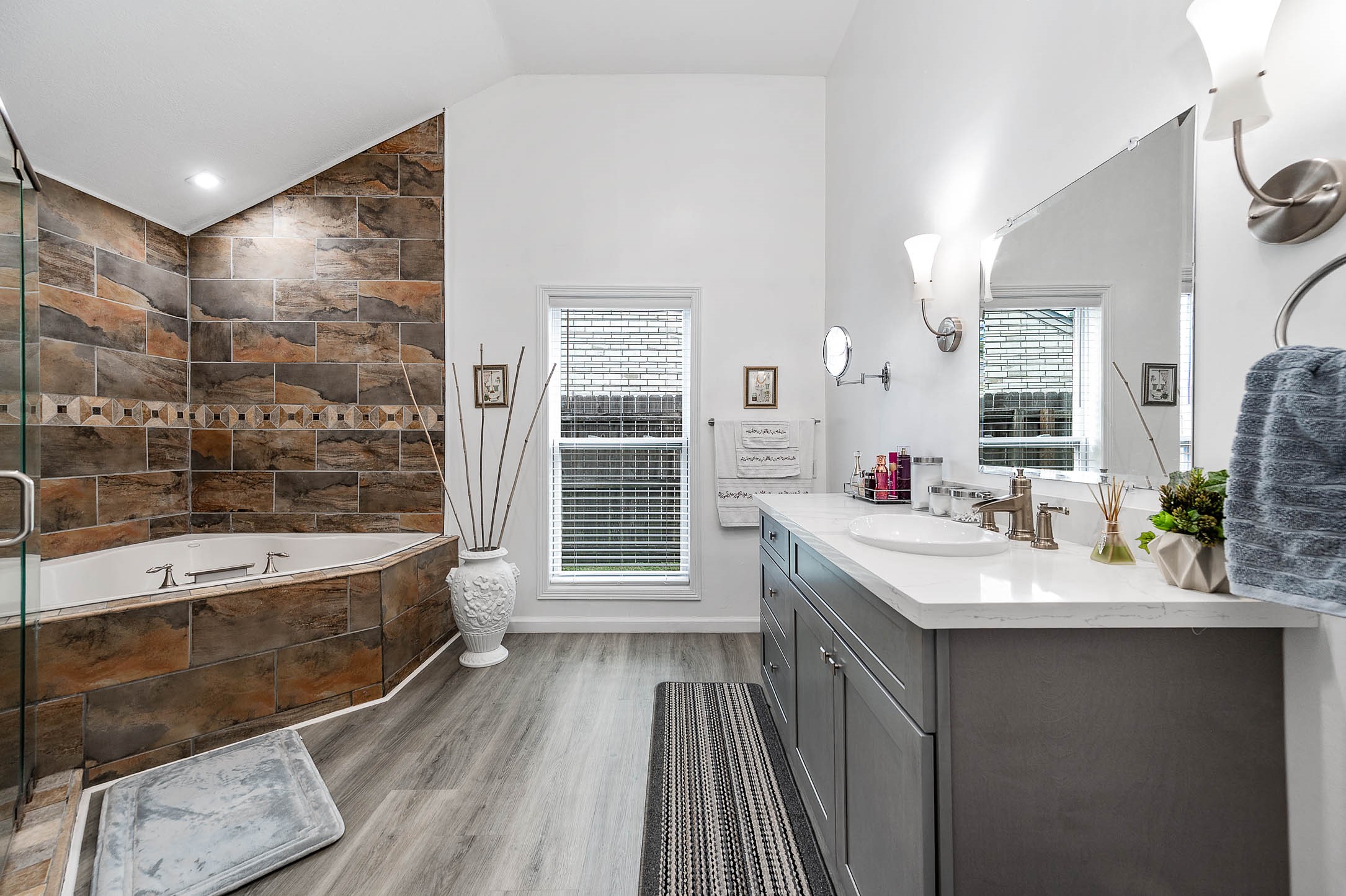 This primary bathroom features a
walk-in shower, separate garden tub,
dark stained cabinets with light
countertops, and sleek modern
finishes!
